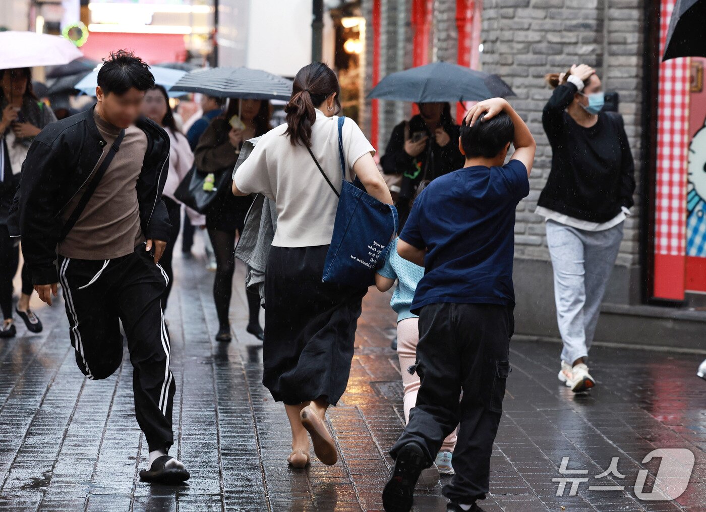 본문 이미지 - 18일 오후 서울 중구 명동거리에서 외국인관광객과 시민들이 내리는 비를 피하고 있다. 2026.10.18 ⓒ 뉴스1 구윤성 기자