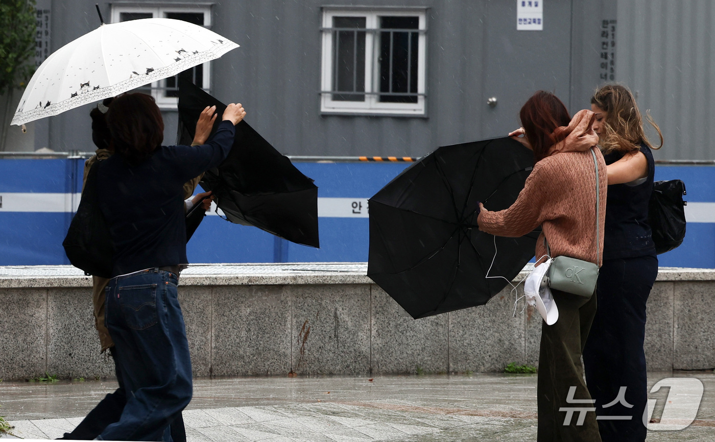 (서울=뉴스1) 최지환 기자 = 중부 지방에 강풍을 동반한 강한 비가 내리는 18일 서울 종로구 보신각 앞에서 시민들의 우산이 강풍에 뒤집혀 있다. 2026.10.18/뉴스1