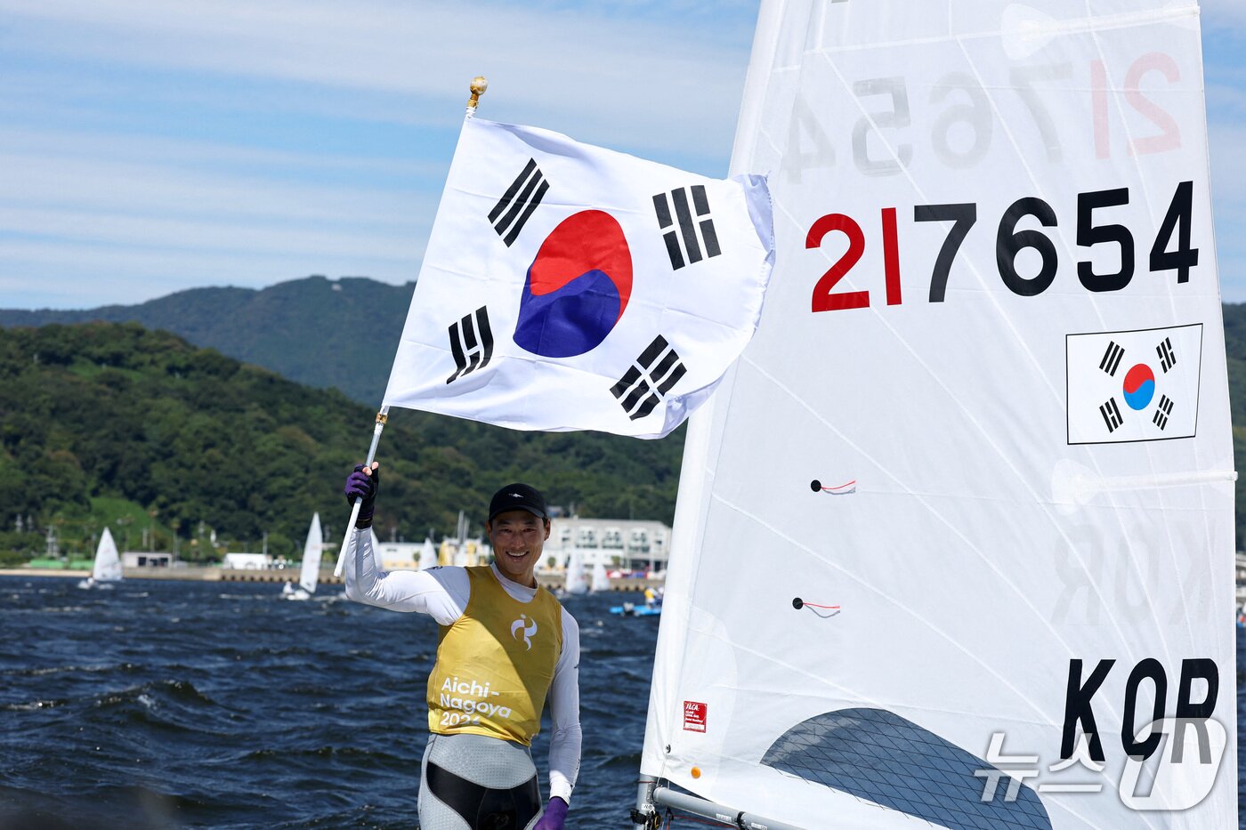 본문 이미지 - 한국 요트의 간판 하지민이 2일 일본 아이치현 가마고리 가이요 요트 항구에서 열린 2026 아이치·나고야 아시안게임 요트 남자 딩기 결승 레이스에서 금메달이 확정되자 태극기를 흔들고 있다. ⓒ 로이터=뉴스1