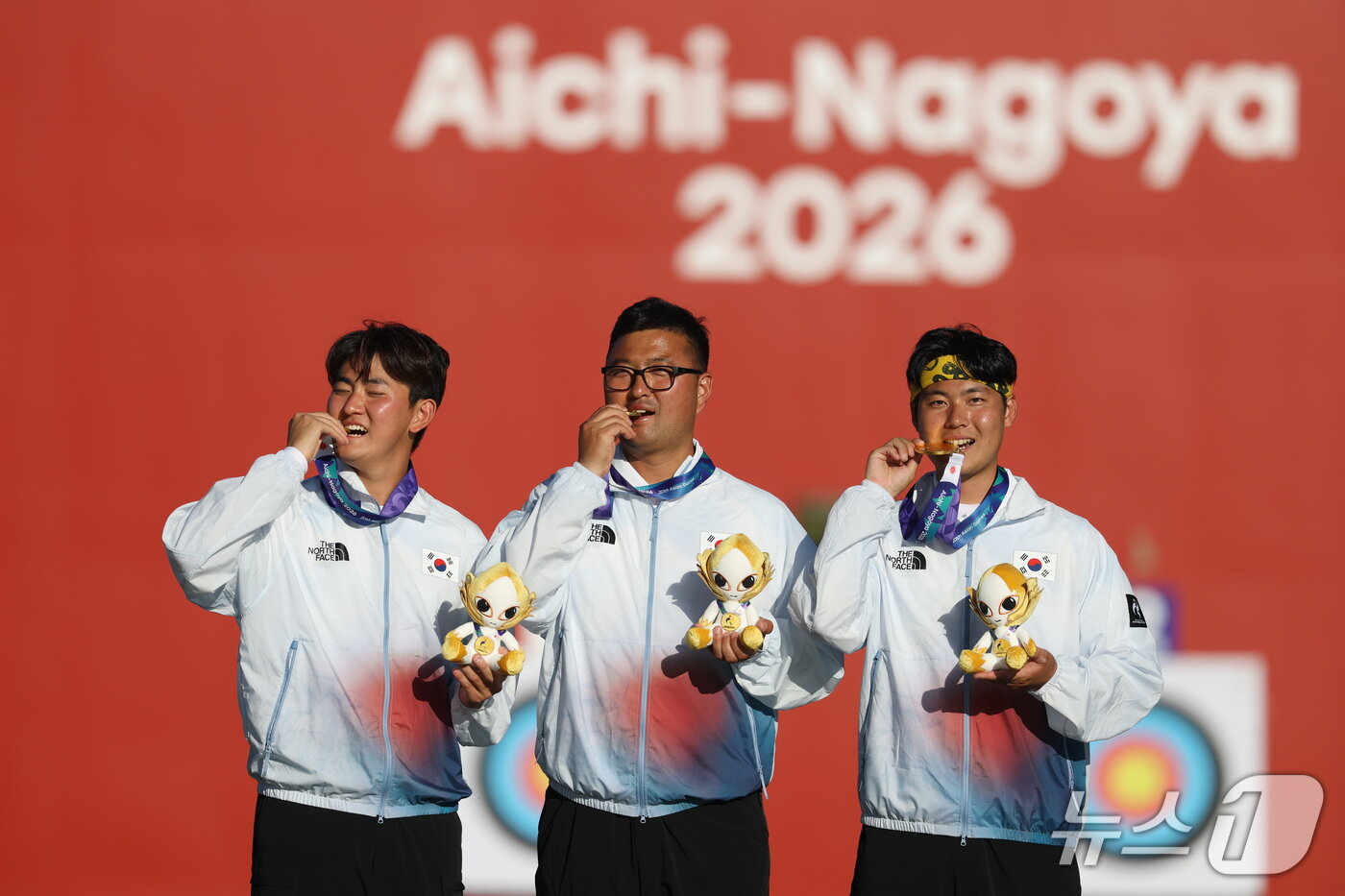 본문 이미지 - 대한민국 김제덕(왼쪽부터), 김우진, 이우석이 2일 일본 오카자키 중앙종합공원 다목적광장에서 열린 2026 아이치·나고야 아시안게임 양궁 리커브 남자 단체전 결승 시상식에서 금메달을 깨물고 세리머니를 하고 있다. 2026.10.2 ⓒ 뉴스1 김민지 기자