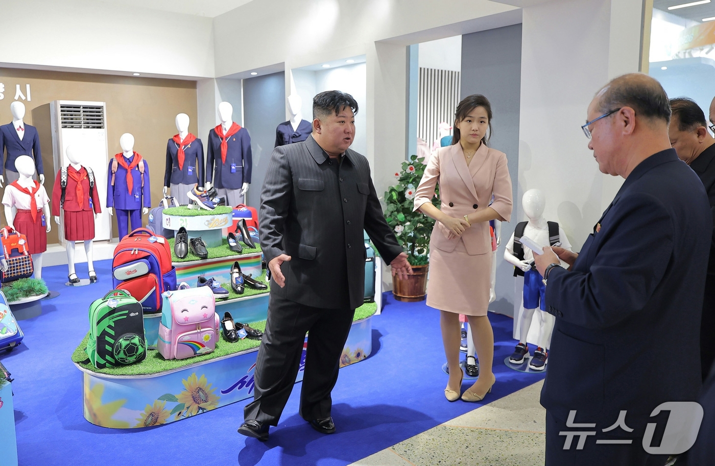 북한 전국피복 신발전시회에서 학생용 가방과 교복을 살펴보는 김정은과 김주애