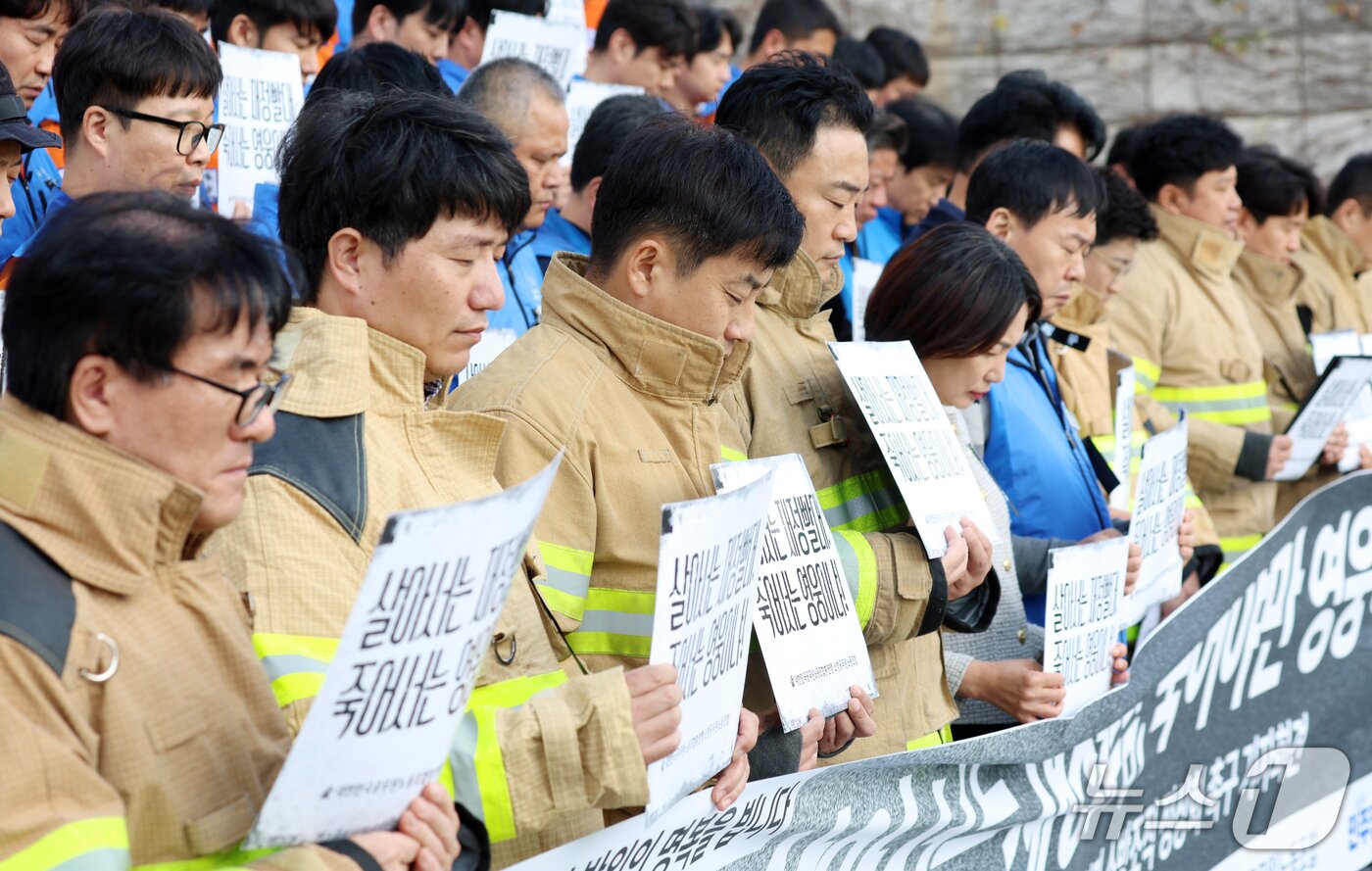 본문 이미지 - 21일 서울 영등포구 여의도 국회의사당 계단에서 열린 대한민국공무원노동조합총연맹 소방공무원노동조합원들이 소방공무원 명예회복과 소방조직 정상화 촉구 기자회견에서 희생된 소방관들에 대한 묵념을 하고 있다. 2026.10.21 ⓒ 뉴스1 김명섭 기자