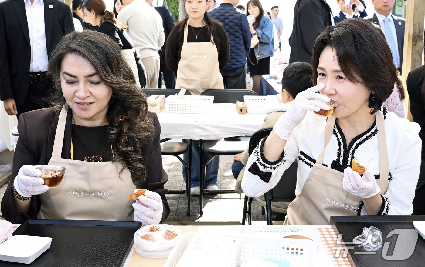 본문 이미지 - 김혜경 여사가 23일 서울 용산구 국립중앙박물관에서 열린 제1회 한식의 날 기념식을 마친 후 전시부스를 방문, 곶감쌈 만들기 체험을 하며 수정과를 맛보고 있다. (청와대통신사진기자단) 2026.10.23 ⓒ 뉴스1