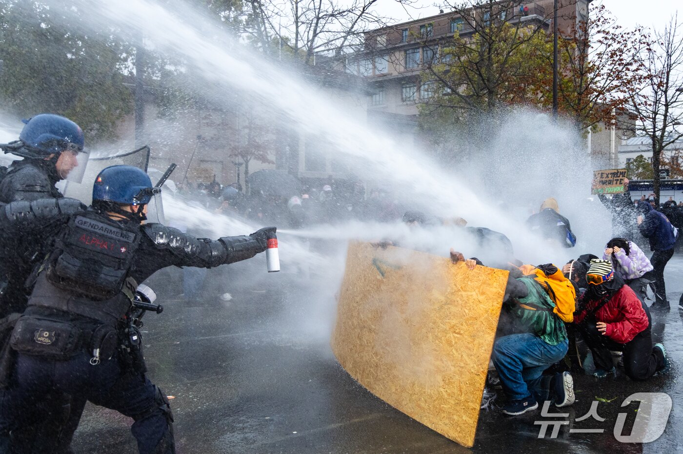 본문 이미지 - 고물가에 항의하고 학생·청년층의 교육여건 개선 요구에 연대하는 프랑스 노란 조끼 등의 2차 집회가 열린 24일(현지시간) 파리에서 프랑스 군사 경찰대원이 물대포를 피하기 위해 합판 뒤에 몸을 숨긴 시위 참가자들을 향해 휴대용 분사기를 사용하고 있다. 2026.10.25 ⓒ 뉴스1 이준성 특파원