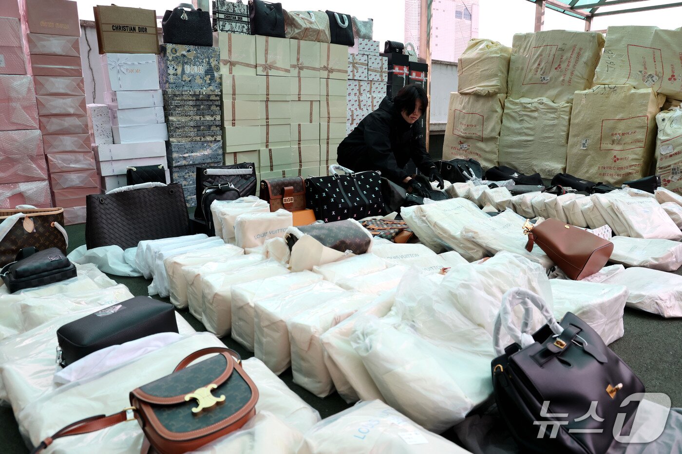 본문 이미지 - 29일 서울 성북경찰서에서 관계자가 샤넬·루이비통 등 유명 해외 명품 브랜드의 가방·지갑 등 시가 355억 원 상당의 압수된 위조상품을 공개하고 있다.  2026.10.29 ⓒ 뉴스1 이광호 기자