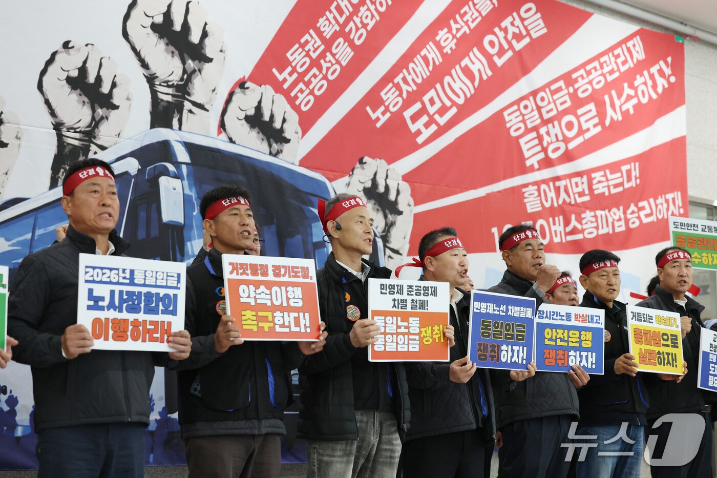 본문 이미지 - 경기지역 버스노조 총파업 예고일을 하루 앞둔 29일 경기 수원시 영통구 경기지방노동위원회에서 한국노총 전국자동차노동조합연맹 경기지역자동차노동조합 관계자들이 2차 조정회의에 앞서 임금 인상을 요구하며 구호를 외치고 있다. 노조는 사측과 합의에 이르지 못할 경우 다음 날인 30일 첫차부터 전면 총파업에 돌입할 예정이다. 2026.10.29 ⓒ 뉴스1 김영운 기자