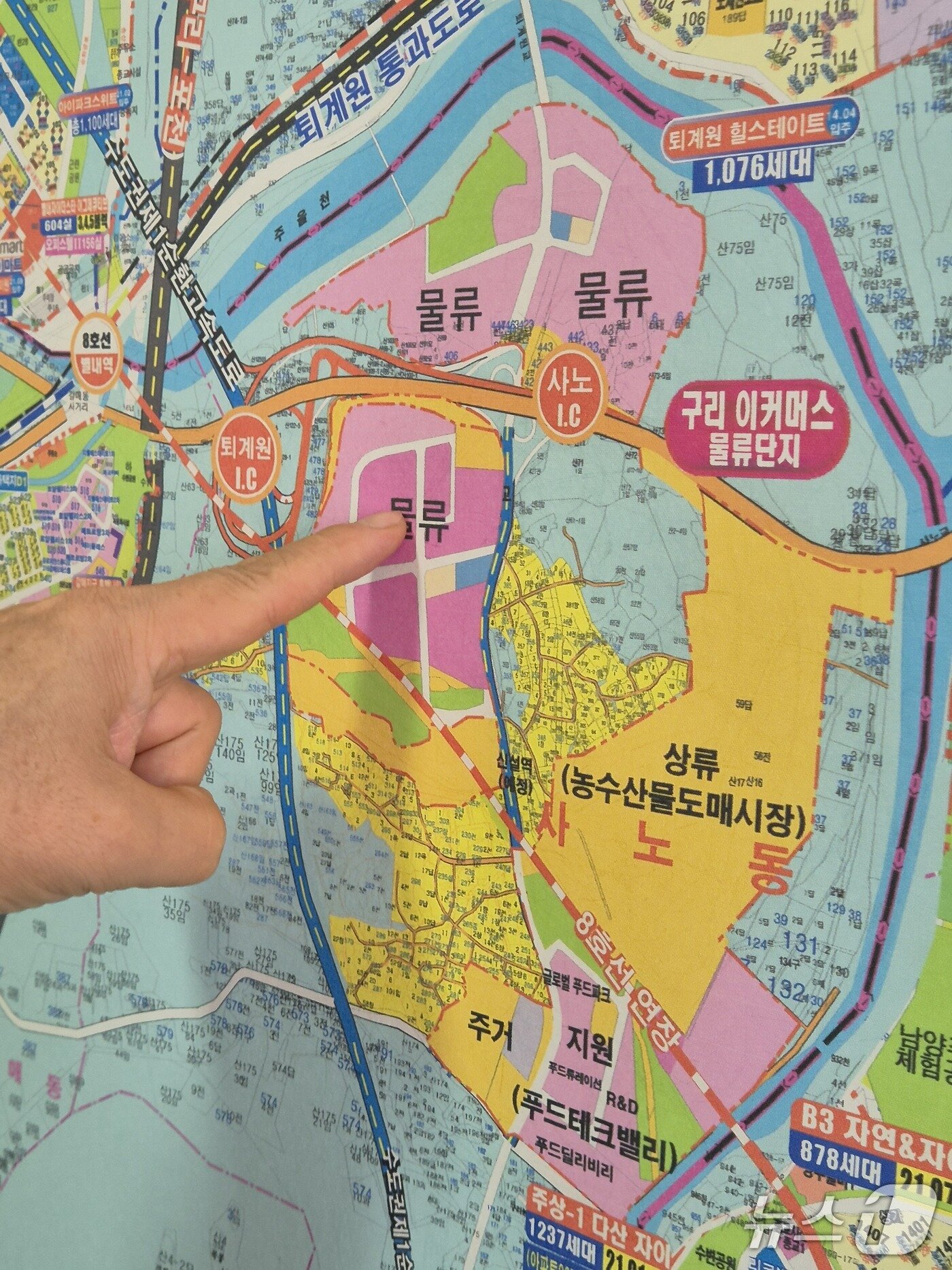 본문 이미지 - 사노동 한 공인중개업소에서 중개사가 신규 택지 개발 예정지를 손으로 가리키고 있다. 2026.10.29/뉴스1 양희문 기자 