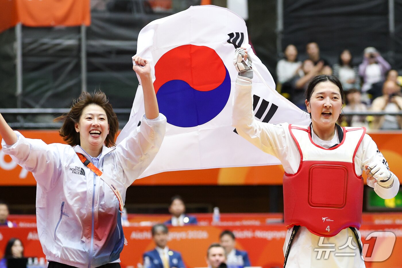 본문 이미지 - 대한민국 송다빈이 3일 일본 도요하시 체육관에서 열린 2026 아이치·나고야 아시안게임 태권도 여자 +67㎏급 결승전에서 중국 무원저를 꺾고 금메달을 확정 짓자 이아름 코치와 태극기를 들고 돌며 기뻐하고 있다. 2026.10.3 ⓒ 뉴스1 안은나 기자