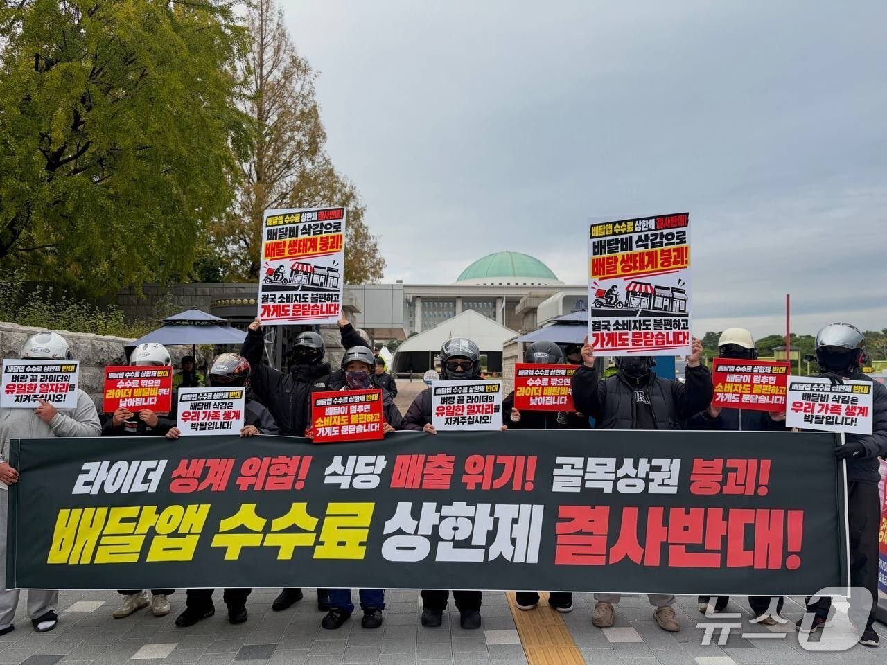 본문 이미지 - 29일 서울 여의도 국회의사당 앞에서 라이더들이 배달앱 수수료 상한제에 반대하는 현수막과 피켓을 들고 있다. 2026.10.30/뉴스1