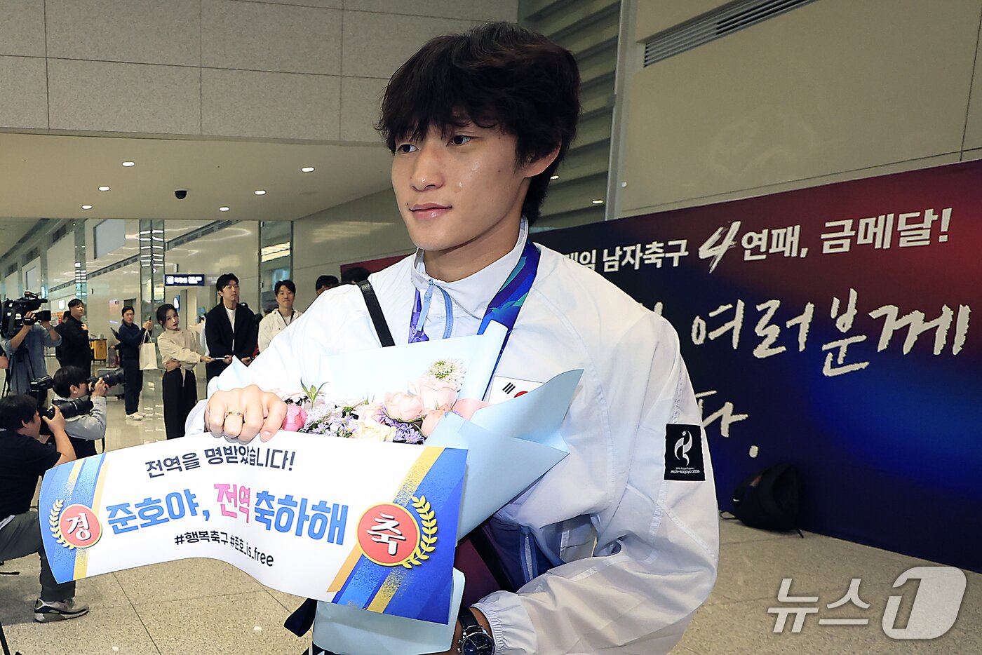 본문 이미지 - 2026 아이치-나고야 아시안게임 남자축구 4연패를 만든 이민성호의 배준호가 4일 오후 인천국제공항을 통해 귀국해 여성팬들이 들어달라는 종이를 들어 포즈를 취하고 있다. 이 종이에는 '전역을 명받았습니다! 경축 준호야, 전역 축하해'라고 적혀있다. 2026.10.4 ⓒ 뉴스1 박정호 기자