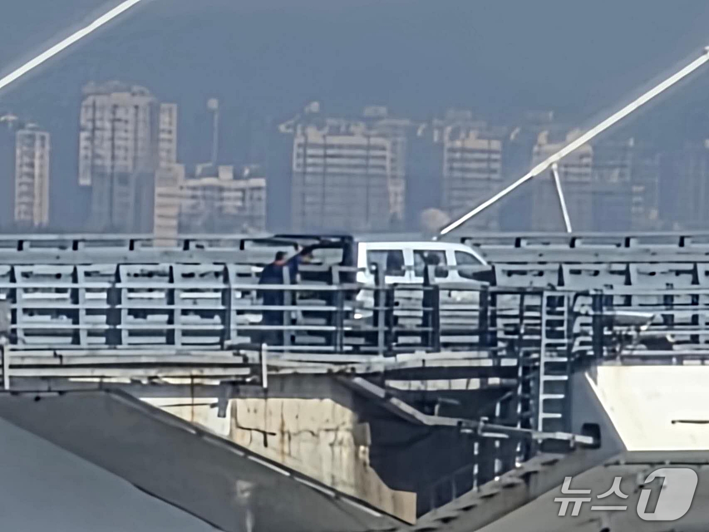 (단둥=뉴스1) 노민호 특파원 = 6일 오전 중국 랴오닝성 단둥에서 바라본 신압록강대교 위에 뒷문이 열린 승합차가 멈춰 서 있고 인부들이 차량 뒤편에 서 있다. 이들의 작업 목적과 …