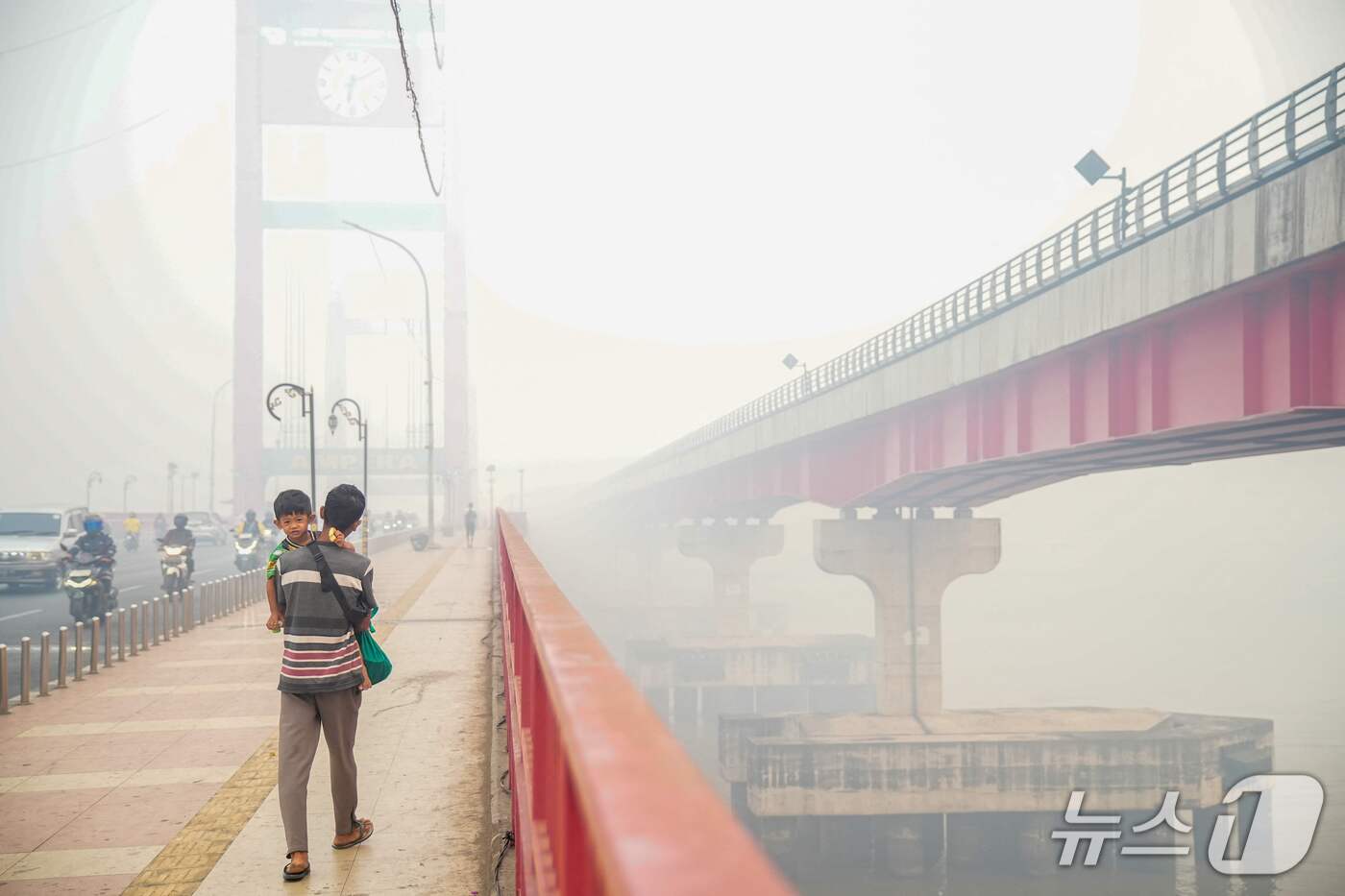(팔렘방 AFP=뉴스1) 김범수 기자 = 5일(현지시간) 인도네시아 남수마트라주 팔렘방의 암페라 다리에서 한 남성이 아이를 안고 걷고 있다. 인도네시아에서는 수주째 산불이 이어지며 …