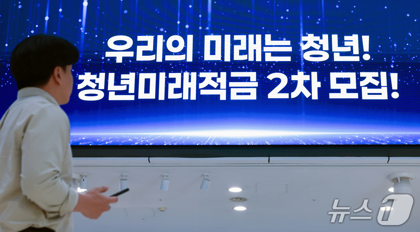 (서울=뉴스1) 이호윤 기자 = 청년미래적금 2차 가입 신청이 시작된 7일 서울 중구 우리은행 본점 스크린에 관련 안내문이 나오고 있다.금융위원회는 청년미래적금 2차 가입신청 기간 …