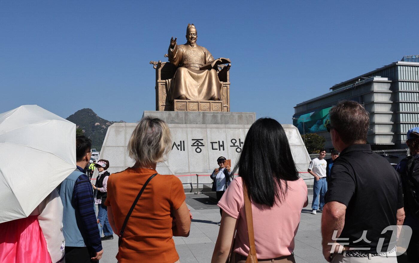 본문 이미지 - 한글날 제정 100주년을 하루 앞둔 8일 서울 종로구 광화문광장에서 시민들과 외국인 관광객들이 세종대왕 동상을 바라보고 있다. 올해는 세종대왕의 훈민정음 반포 580주년이자 한글날 제정 100주년을 맞는 해다. 2026.10.8 ⓒ 뉴스1 박지혜 기자