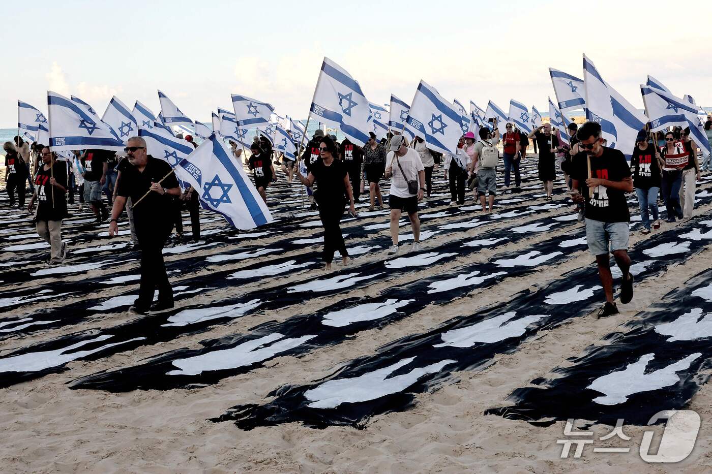 (텔아비브 AFP=뉴스1) 김범수 기자 = 7일(현지시간) 이스라엘 텔아비브 해변에 2023년 10월 7일 하마스 공격 3주기를 맞아 설치된 추모 조형물 사이로 이스라엘 국기를 든 …