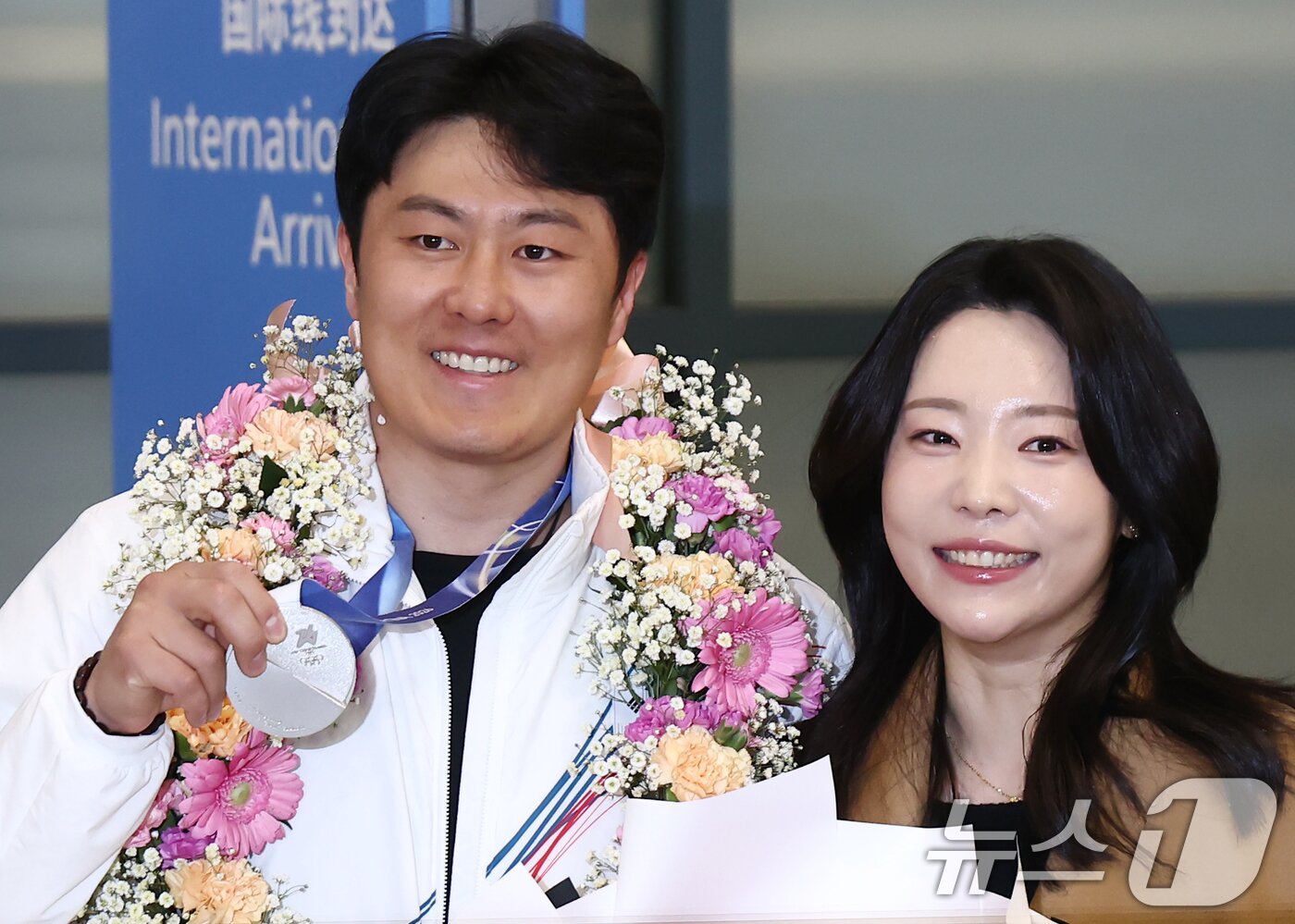 본문 이미지 - 2026 밀라노·코르티나담페초 동계 올림픽에서 한국에 400번째 올림픽 메달을 안겨준 스노보드 김상겸이 10일 오전 인천국제공항을 통해 귀국하며 은메달을 들어보이고 있다. 오른쪽은 아내 박한솔 씨. 2026.2.10 ⓒ 뉴스1 김민지 기자