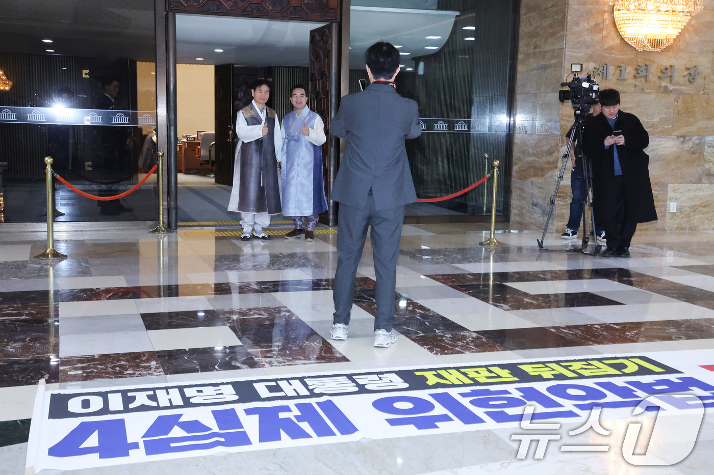 (서울=뉴스1) 신웅수 기자 = 한복을 입은 박홍근 더불어민주당 의원이 12일 서울 여의도 국회 로텐더홀에서 기념 촬영을 하는 가운데 국민의힘이 제작한 규탄 현수막이 놓여져 있다. …