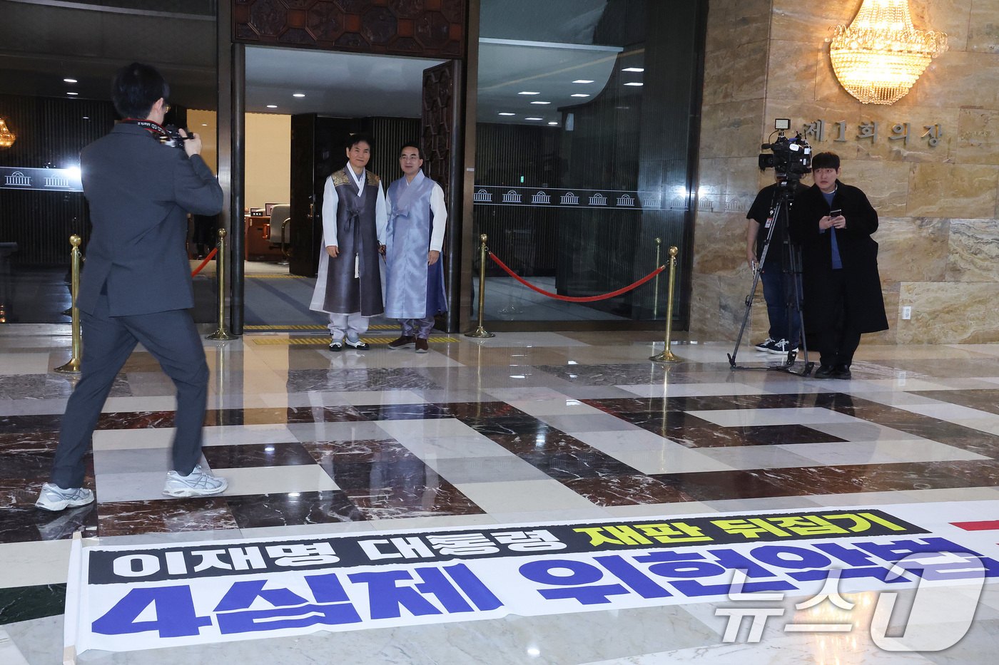 (서울=뉴스1) 신웅수 기자 = 한복을 입은 박홍근 더불어민주당 의원이 12일 서울 여의도 국회 로텐더홀에서 기념 촬영을 하는 가운데 국민의힘이 제작한 규탄 현수막이 놓여져 있다. …