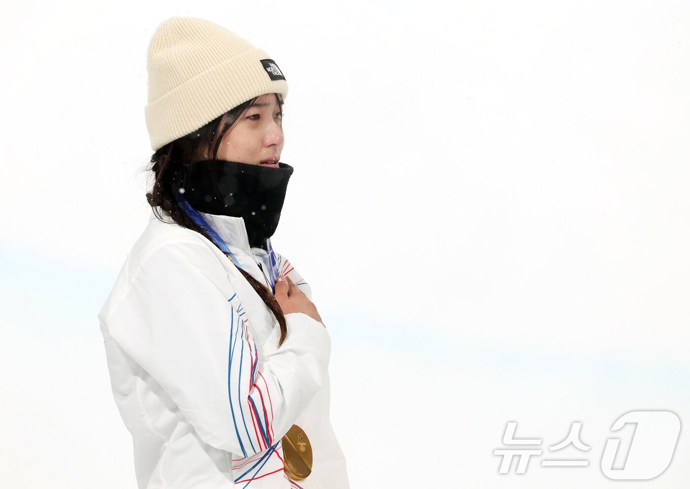 본문 이미지 - 12일(현지시간) 이탈리아 리비뇨 스노파크에서 열린 2026 밀라노·코르티나담페초 동계올림픽 스노보드 여자 하프파이프 결선에서 90.25점을 받아 금메달을 획득한 스노보드 최가온이 눈물을 흘리며 국민의례를 하고 있다. 2026.2.13 ⓒ 뉴스1 김진환 기자