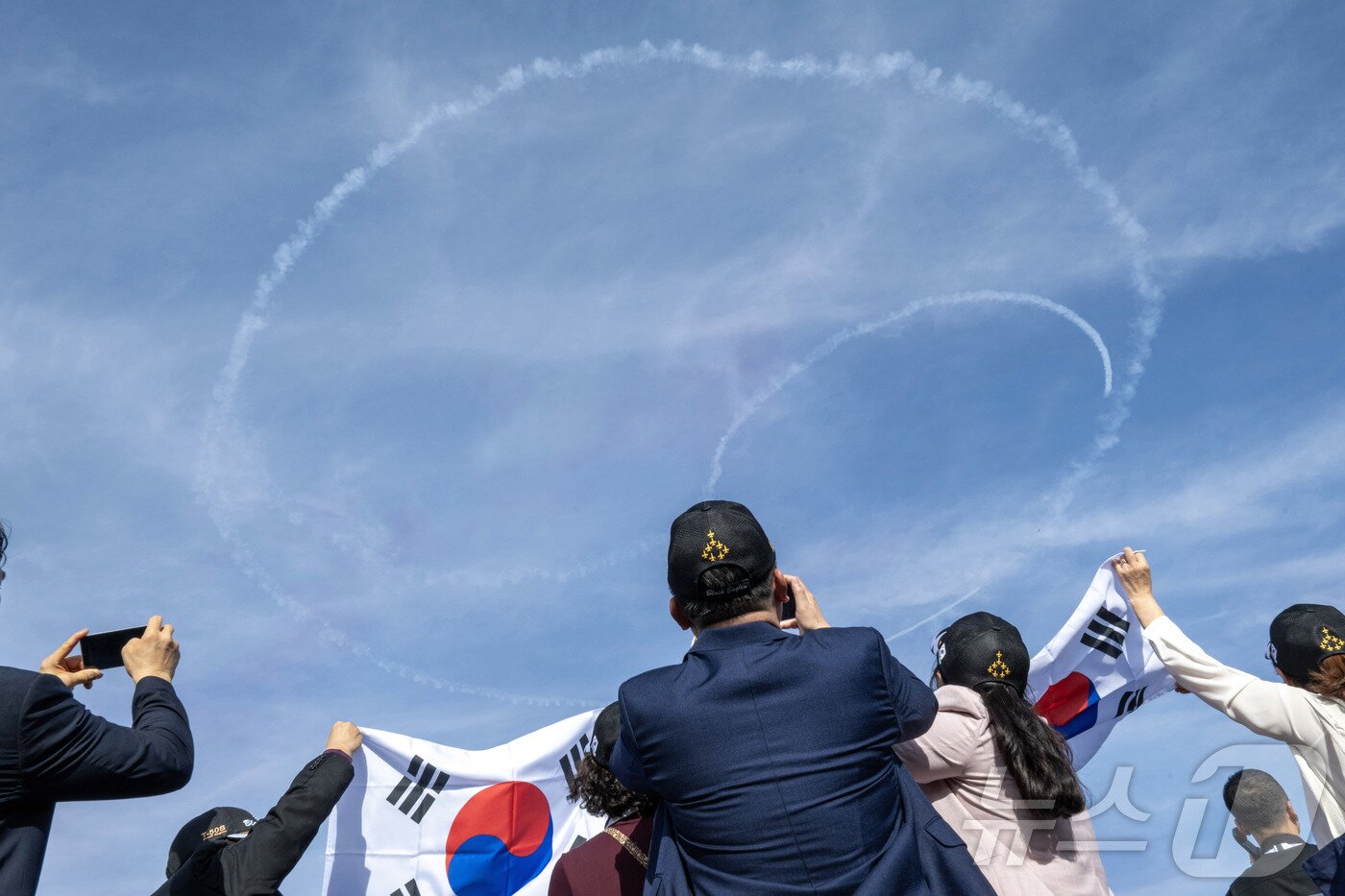 본문 이미지 - 공군은 특수비행팀 블랙이글스가 8일부터 12일(현지시간)까지 사우디아라비아 리야드에서 열린 ‘세계 방위산업 전시회(WDS 2026)’에 참가해 에어쇼를 선보였다고 13일 밝혔다. 사진은 지난 9일(현지시간) 행사장을 찾은 한인 교민들이 블랙이글스의 태극 문양 기동을 관람하는 모습. (공군 제공. 재판매 및 DB 금지) 2026.2.13 ⓒ 뉴스1