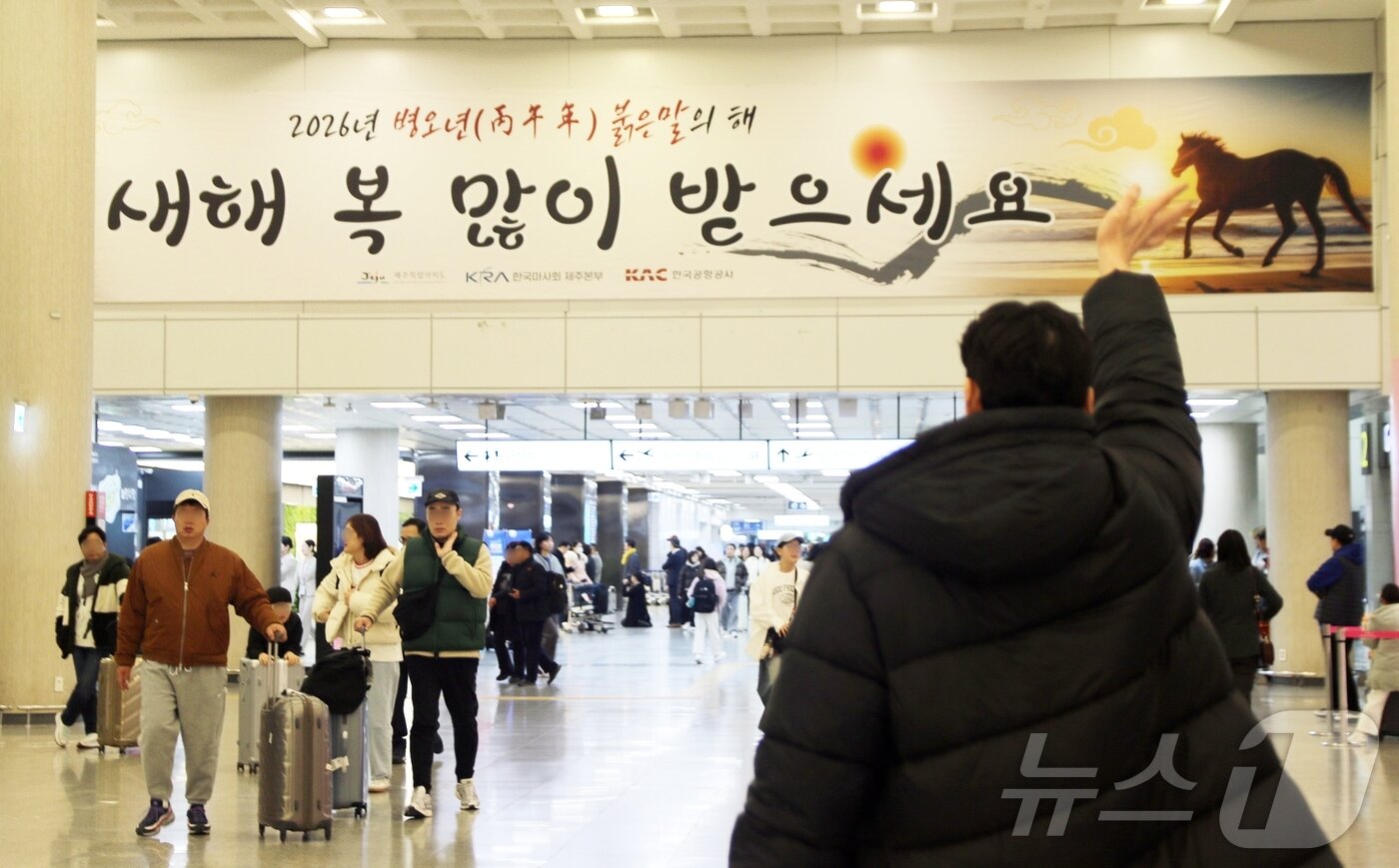 본문 이미지 - 설 연휴가 시작된 14일 오전 제주국제공항 1층에서 시민이 손을 흔들며 인사하고 있다. 제주도관광협회에 따르면 이번 연휴 동안 제주도에는 입도객 24만5000여 명이 올 것으로 예상된다.2026.2.14 ⓒ 뉴스1 홍수영 기자