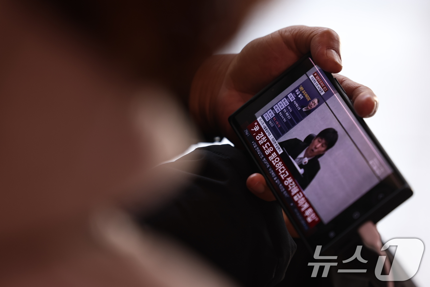 (서울=뉴스1) 구윤성 기자 = 19일 오후 서울역 대합실에서 한 시민이 휴대폰으로 윤석열 전 대통령의 내란 우두머리 혐의 1심 선고 생중계를 바라보고 있다. 2026.2.19/뉴 …