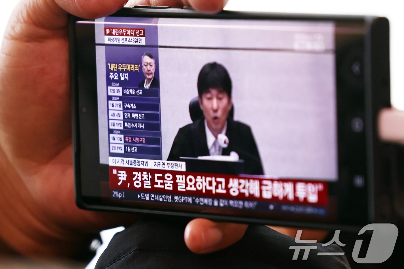 본문 이미지 - 19일 오후 서울역 대합실에서 한 시민이 휴대폰으로 윤석열 전 대통령의 내란 우두머리 혐의 1심 선고 생중계를 바라보고 있다. 2026.2.19 ⓒ 뉴스1