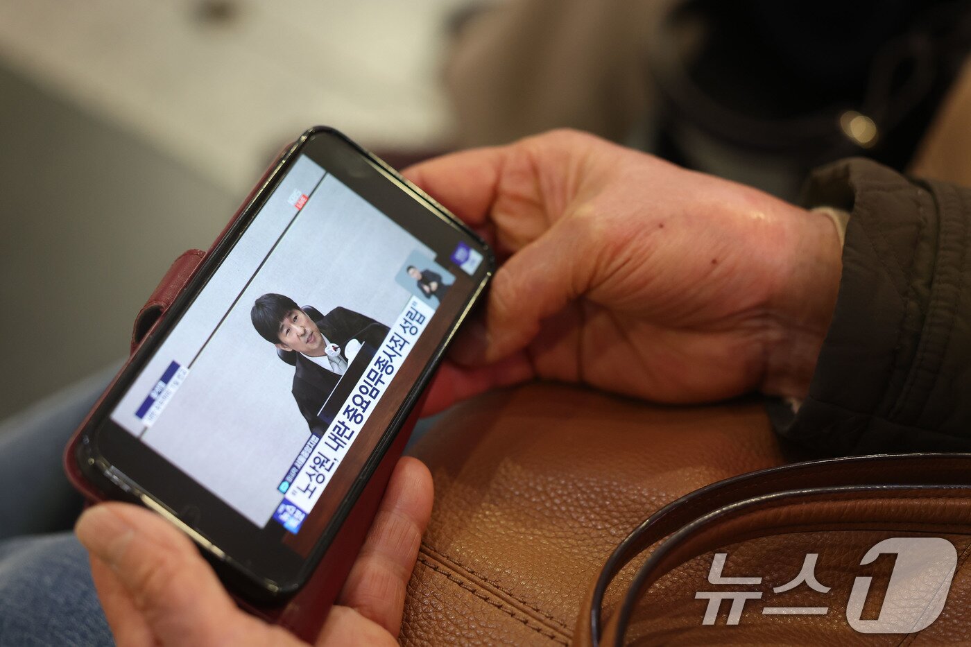 본문 이미지 - 19일 오후 광주 서구 광천동 유스퀘어복합터미널에서 시민들이 윤석열 전 대통령의 내란 우두머리 혐의 1심 선고를 핸드폰으로 지켜보고 있다. 윤 전 대통령은 2024년 12월 3일 비상계엄을 선포한 지 443일 만에 무기징역을 선고받았다. 2026.2.19 ⓒ 뉴스1 박지현 기자