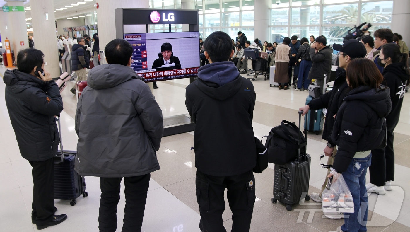 (제주=뉴스1) 홍수영 기자 = 19일 오후 제주국제공항 3층 출발장에서 여행객들이 윤석열 전 대통령의 내란 우두머리 혐의에 대한 1심 선고를 지켜보고 있다.2026.2.19/뉴스 …