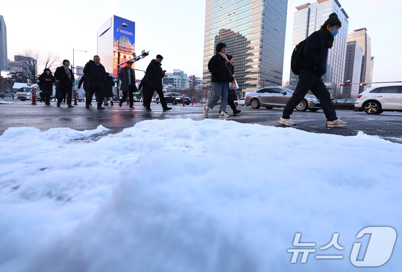 본문 이미지 - 2일 오전 서울 종로구 세종대로에서 밤새 내려 쌓인 눈 뒤로 출근길 시민들이 발걸음을 옮기고 있다. 2026.2.2/뉴스1 ⓒ News1 구윤성 기자