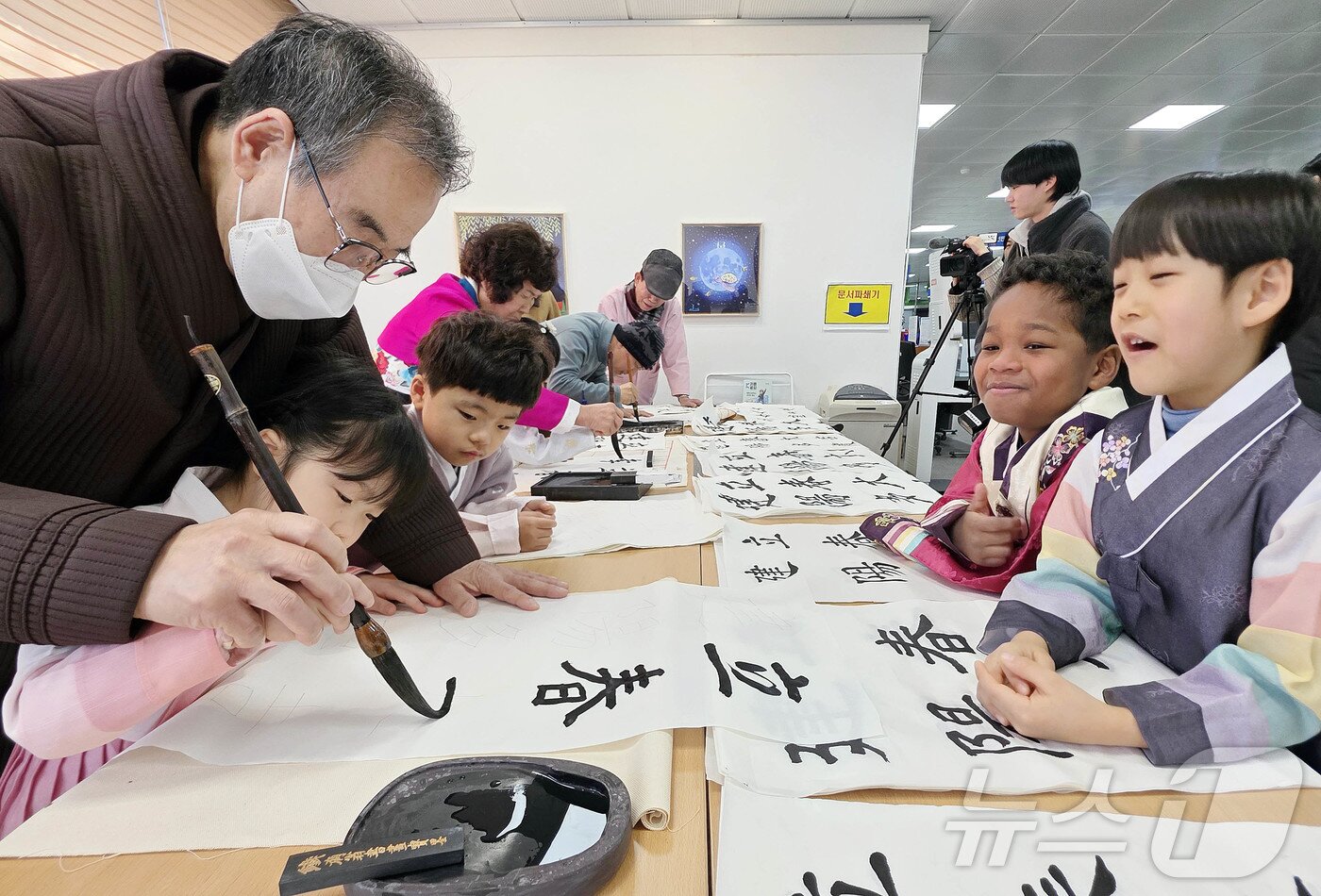 본문 이미지 - 절기상 입춘을 이틀 앞둔 2일 광주 북구청 민원실에서 열린 입춘대길 휘호 제작 무료배부 행사에서 노인복지센터 서예 동아리반 회원들이 중흥하나어린이집 아이들에게 입춘방 쓰는 법을 알려주고 있다.(광주 북구 제공. 재판매 및 DB 금지) 2026.2.2/뉴스1 ⓒ News1 박지현 기자