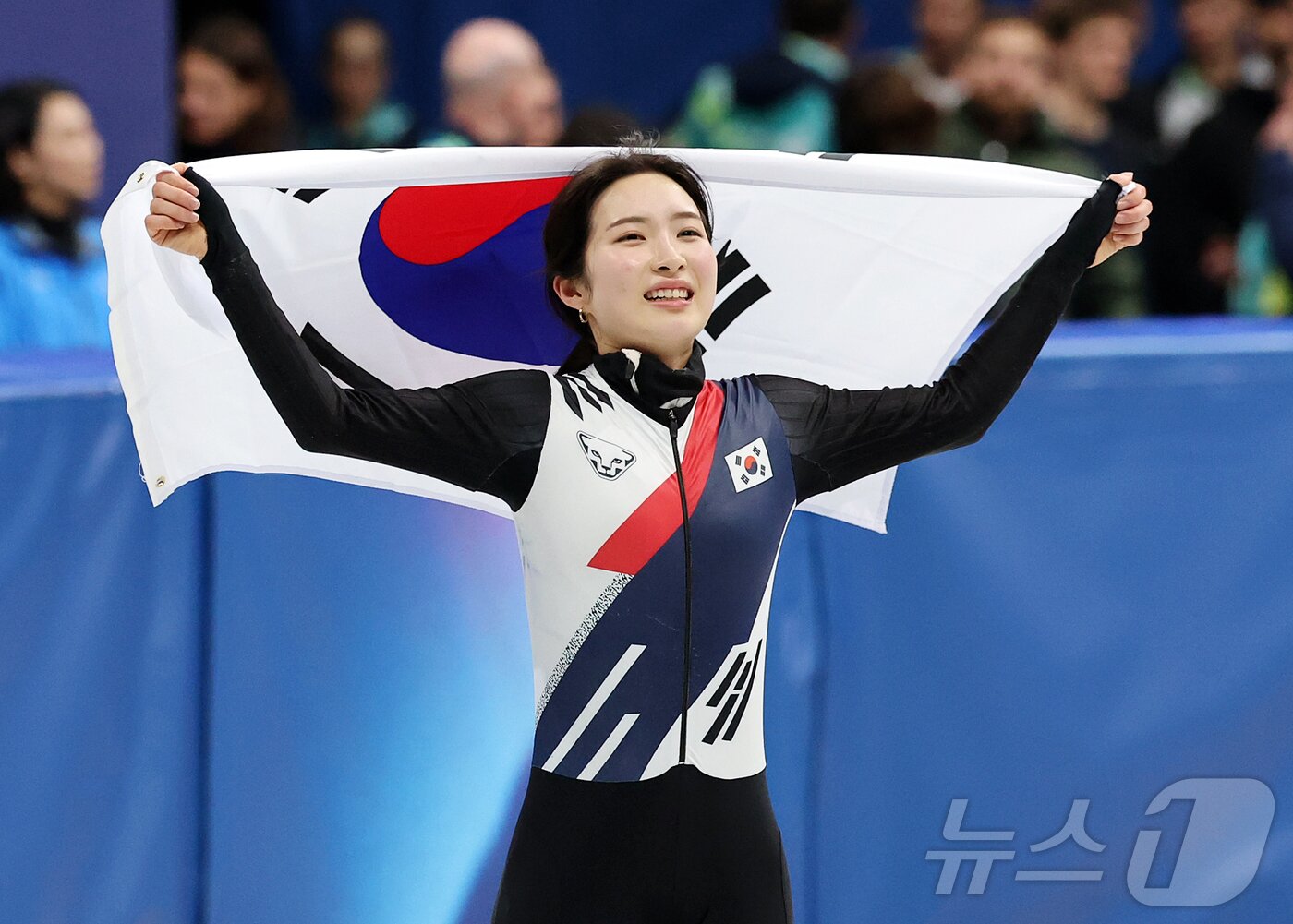 본문 이미지 - 쇼트트랙 김길리가 20일(현지시간) 이탈리아 밀라노 아이스 스케이팅 아레나에서 열린 2026 밀라노·코르티나담페초 동계올림픽 쇼트트랙 여자 1500m 결승에서 금메달을 확보한 후 태극기를 두른 채 인사하고 있다. 2026.2.21 ⓒ 뉴스1 김진환 기자