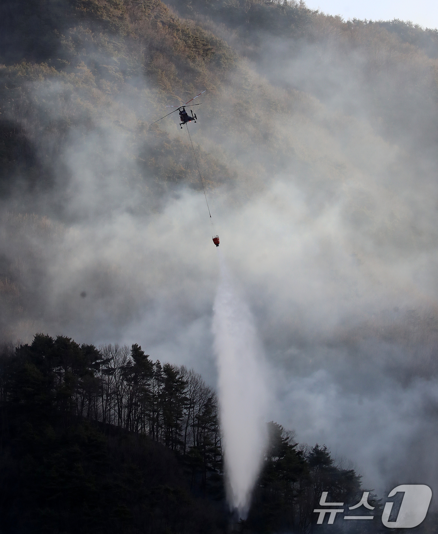 (함양=뉴스1) 윤일지 기자 = 경남 함양 산불 사흘째인 23일 오전 함양군 마천면 창원리 야산에서 산불진화 헬기가 진화 작업을 벌이고 있다. 2026.2.23/뉴스1