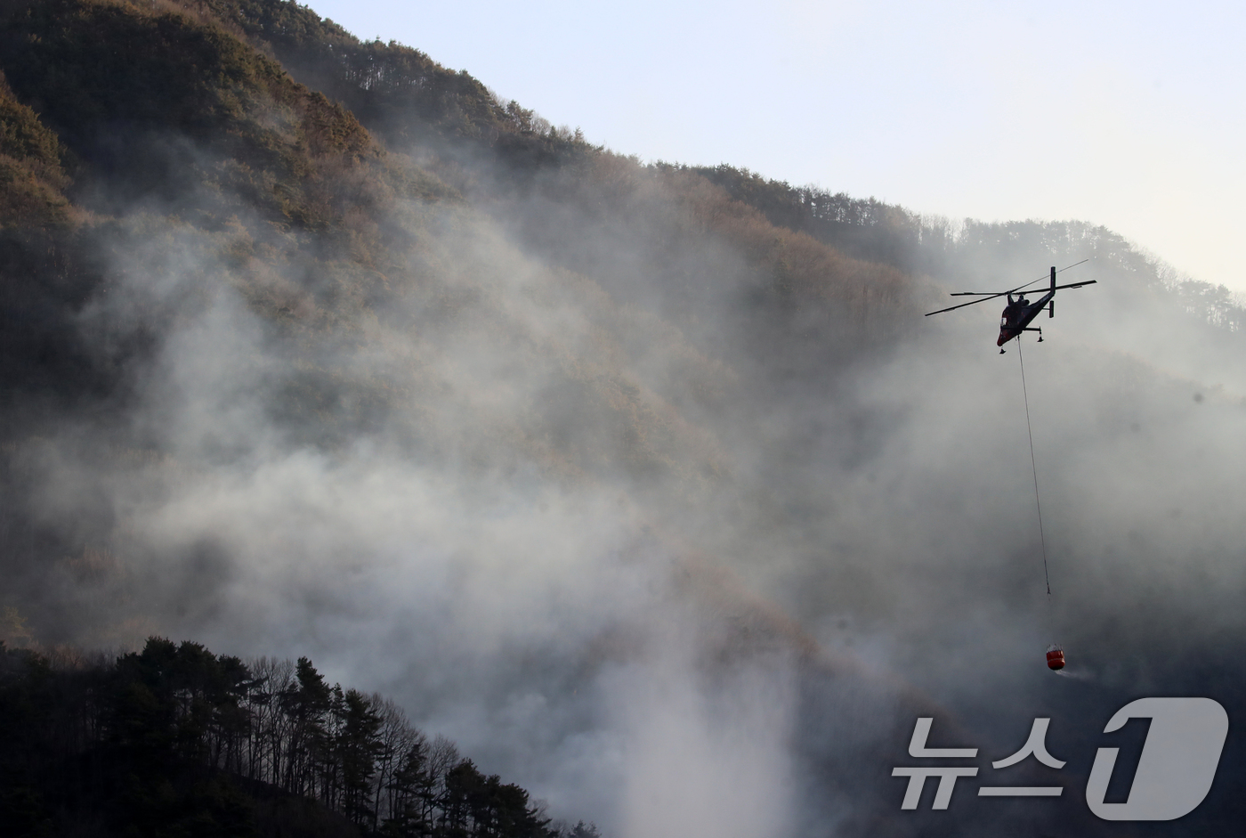 (함양=뉴스1) 윤일지 기자 = 경남 함양 산불 사흘째인 23일 오전 함양군 마천면 창원리 야산에서 산불진화 헬기가 진화 작업을 벌이고 있다. 2026.2.23/뉴스1