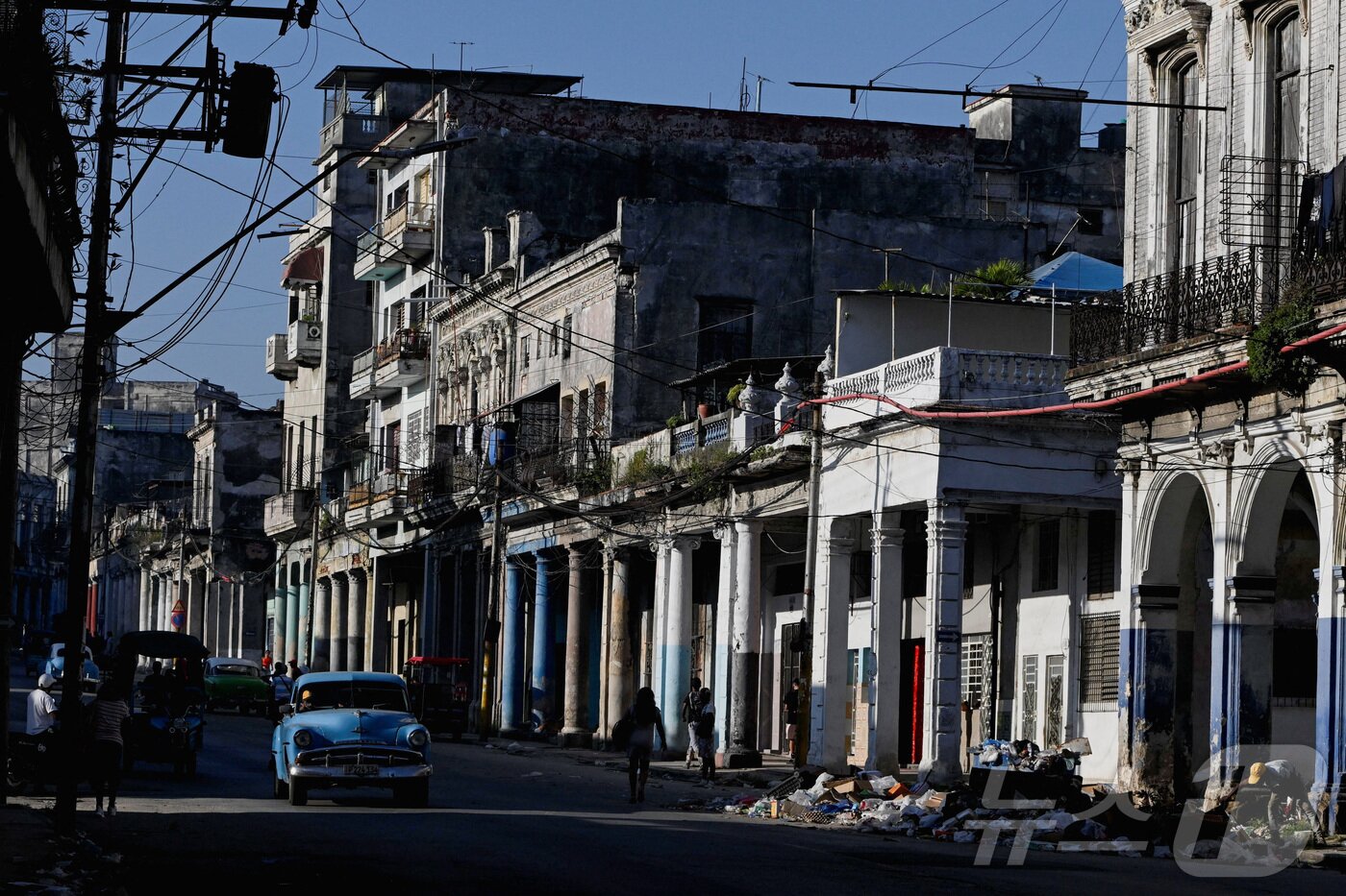 본문 이미지 - 16일(현지시간) 쿠바 아바나 시내 거리에서 올드카 한 대가 쓰레기 더미 옆을 지나가고 있다. 2026.02.16 ⓒ 로이터=뉴스1