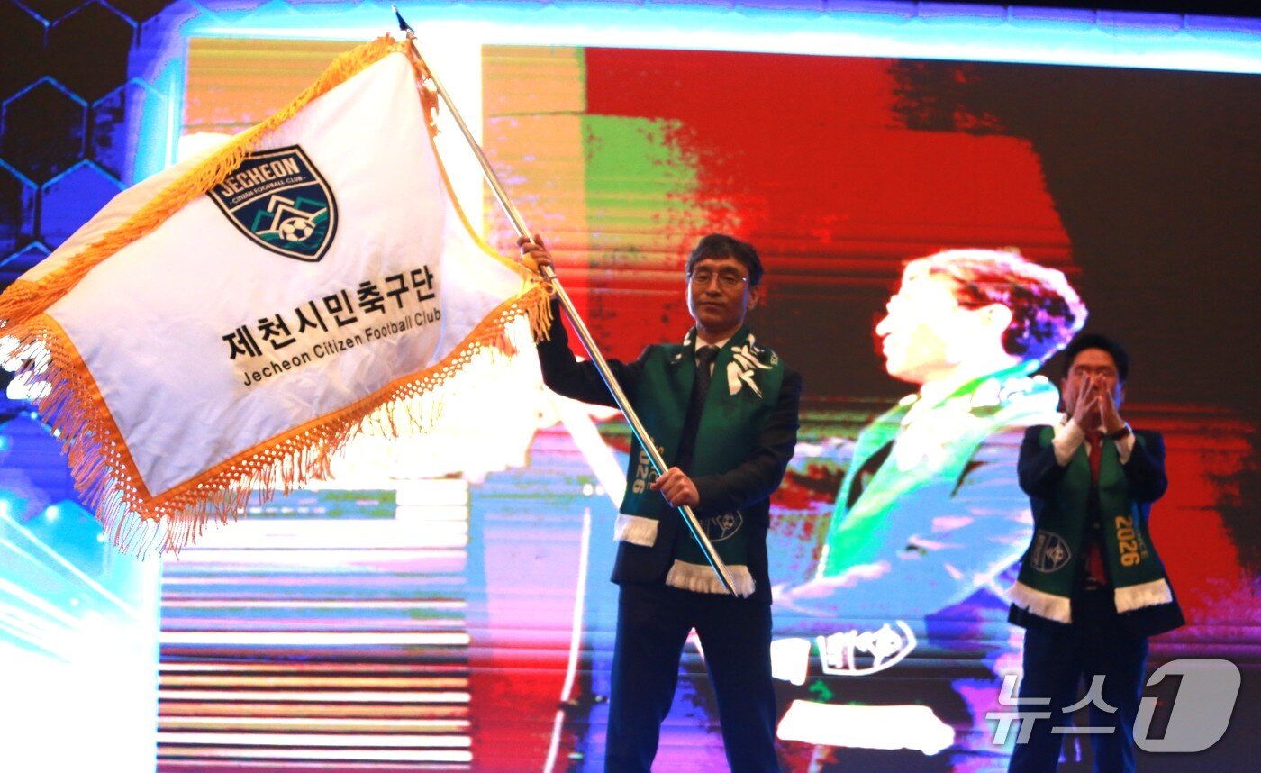 본문 이미지 -  안성국 제천시민축구단 대표이사가 김창규 구단주에게 구단기를 전달받고 힘차게 흔들고 있다.2026. 2.24 ⓒNews1 /뉴스1 손도언 기자