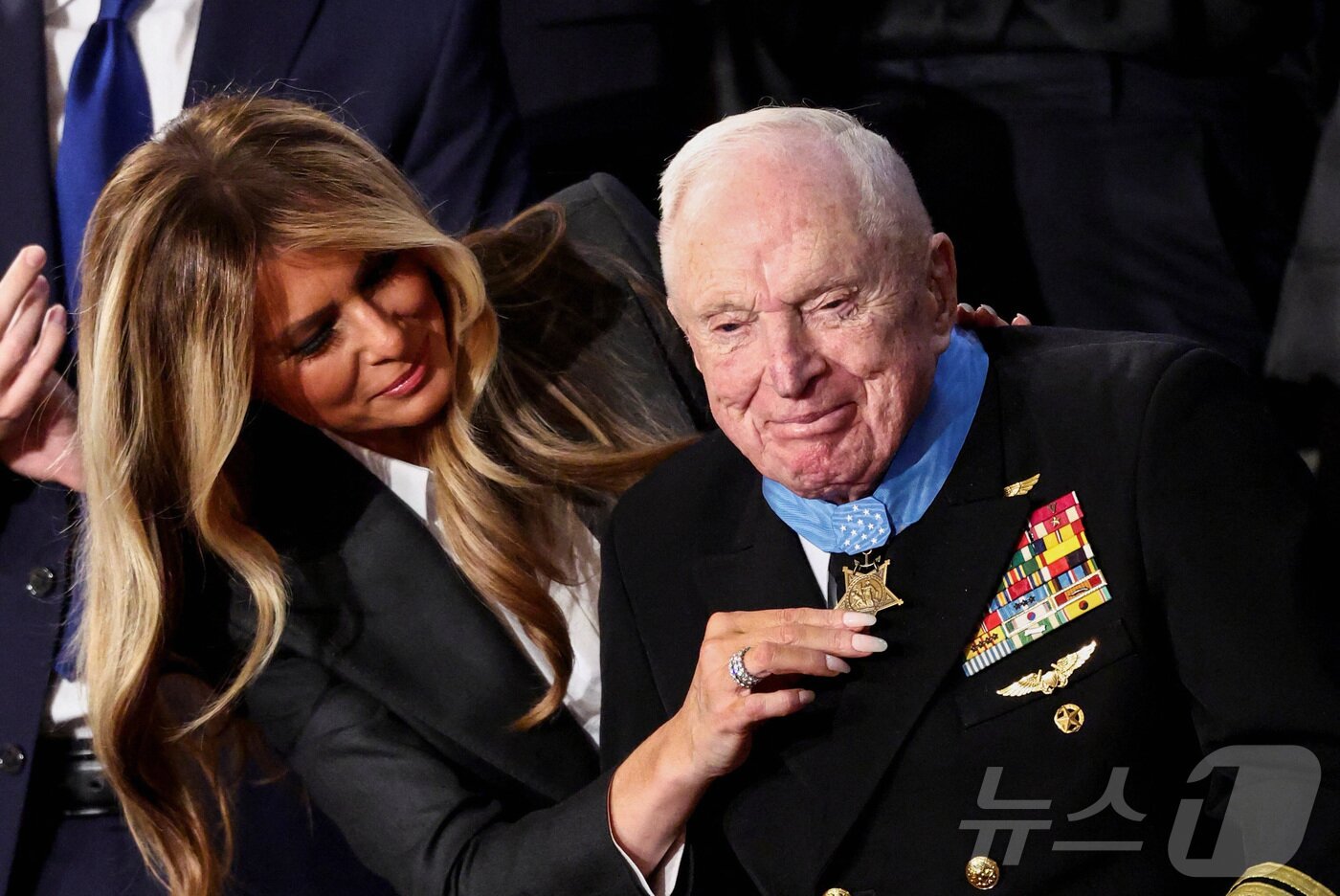 본문 이미지 - 24일(현지시간) 워싱턴 DC 미국 국회의사당 하원 회의장에서 열린 도널드 트럼프 미국 대통령의 2기 첫 국정연설 중 영부인 멜라니아 여사가 한국전쟁 참전용사 로이스 윌리엄스(100세)에게 의회 명예 훈장을 수여하고 있다. 2026.02.24. ⓒ 로이터=뉴스1