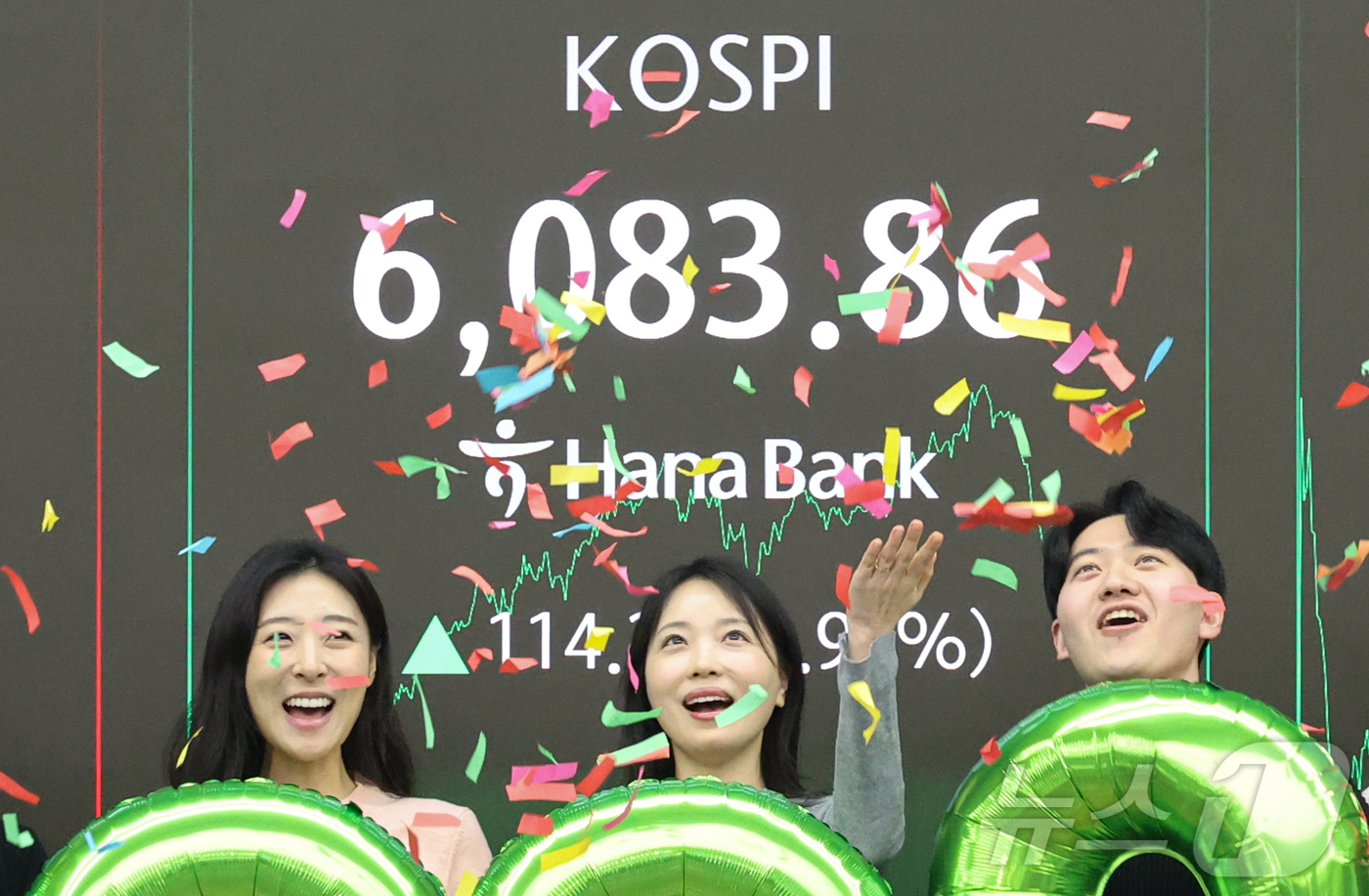 (서울=뉴스1) 황기선 기자 = 코스피가 종가 기준 사상 처음 6000선을 돌파한 25일 오후 서울 중구 하나은행 본점 딜링룸에서 직원들이 축하 세리머니를 하고 있다. 이날 코스피 …