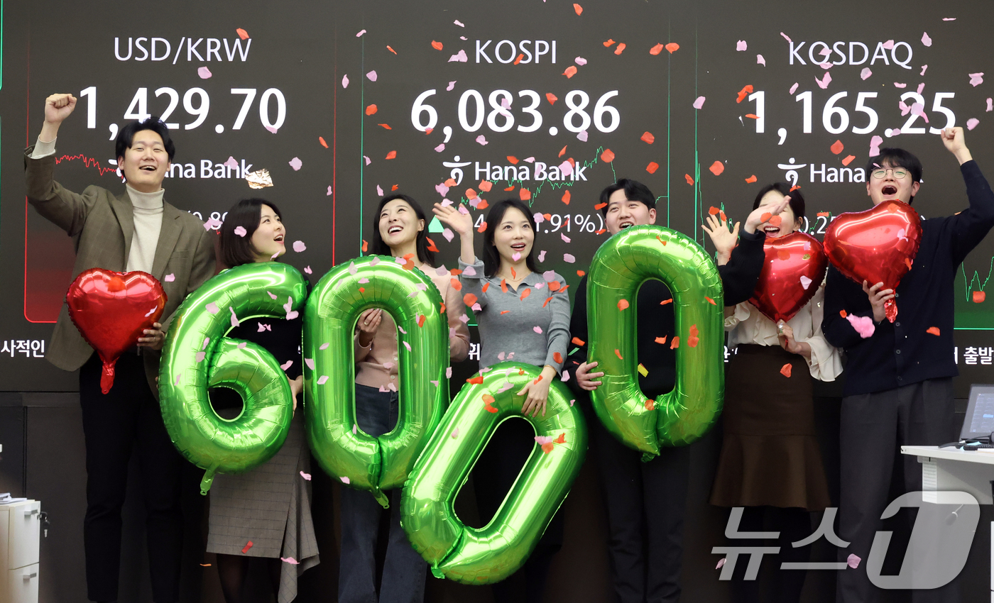 (서울=뉴스1) 황기선 기자 = 코스피가 종가 기준 사상 처음 6000선을 돌파한 25일 오후 서울 중구 하나은행 본점 딜링룸에서 직원들이 축하 세리머니를 하고 있다.이날 코스피지 …