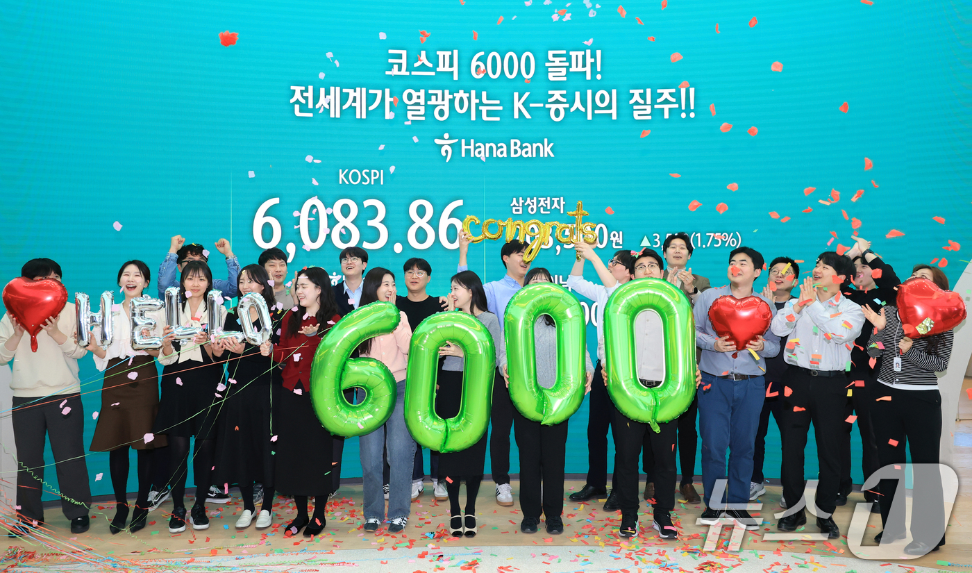 (서울=뉴스1) 황기선 기자 = 코스피가 종가 기준 사상 처음 6000선을 돌파한 25일 오후 서울 중구 하나은행 본점 딜링룸에서 직원들이 축하 세리머니를 하고 있다.이날 코스피지 …