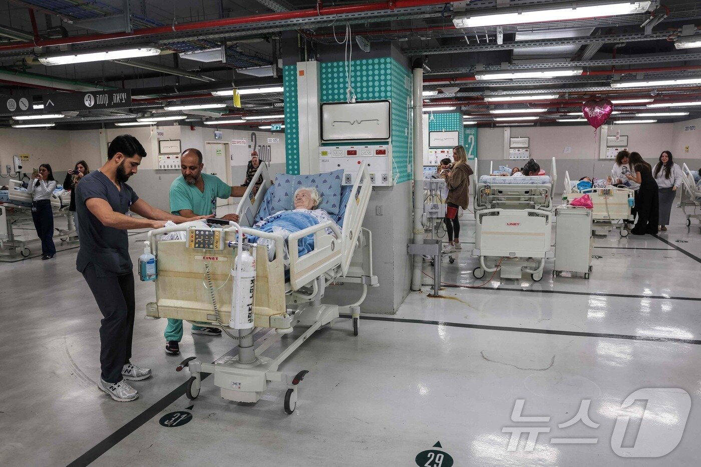 본문 이미지 - 28일(현지시간) 이스라엘 텔아비브의 한 병원 주차장에서 직원들이 환자들을 치료하고 있다. 이날 이스라엘 군 당국은 미국과 함께 이란을 전격 공격하면서 이스라엘 전역에서 공습경보 사이렌을 울렸다. 2026.02.28 ⓒ AFP=뉴스1