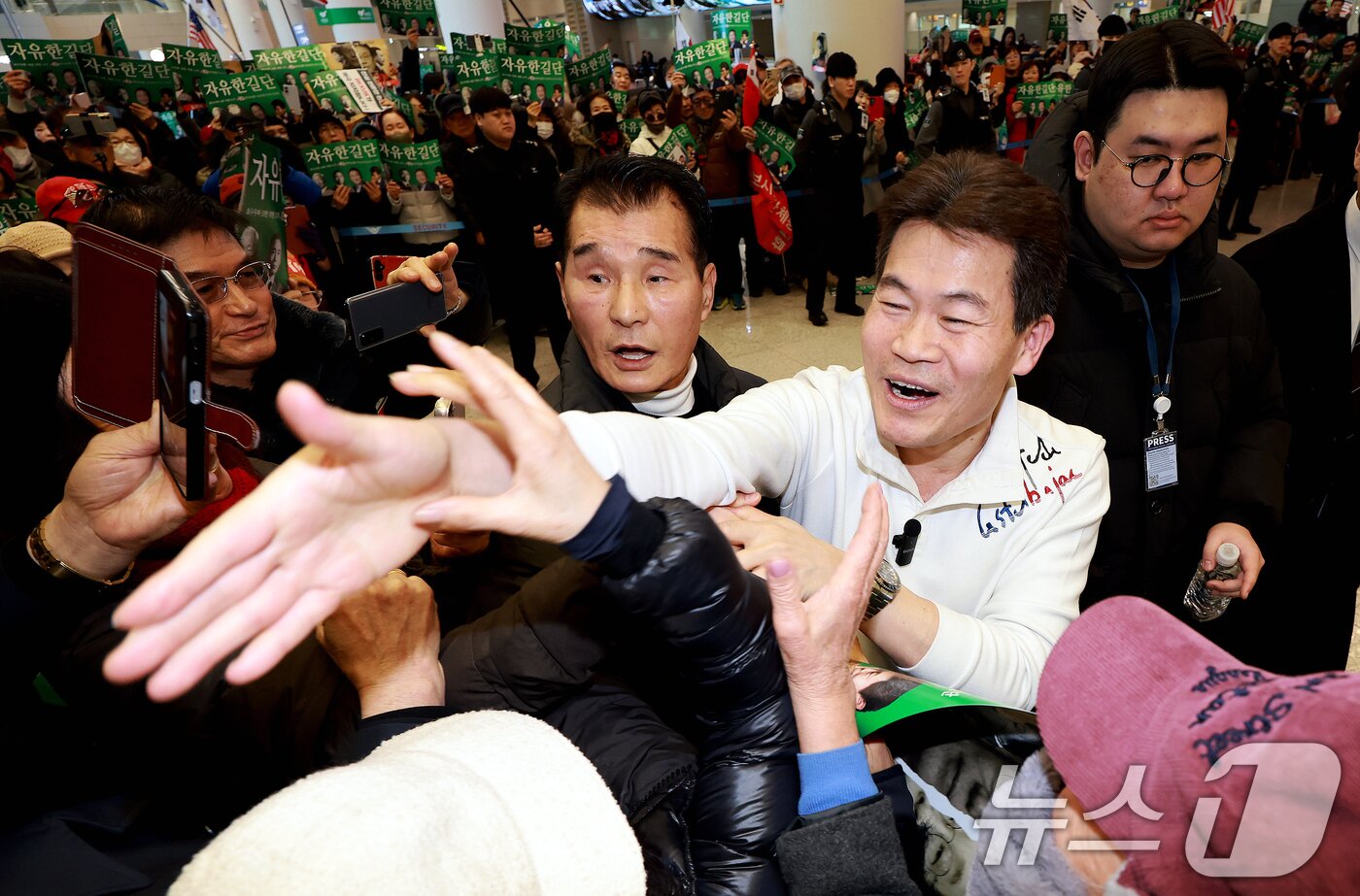 본문 이미지 - 전한길 전 한국사 강사가 지난 3일 인천국제공항 제2여객터미널로 귀국해 지지자들을 향해 손을 뻗고 있다. 2026.2.3 ⓒ 뉴스1 이호윤 기자