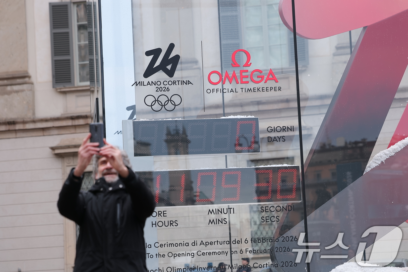 (밀라노=뉴스1) 김성진 기자 = 2026 밀라노·코르티나 동계올림픽 개막일인 6일(현지시간) 이탈리아 밀라노 두오모 광장 인근에서 관광객이 올림픽 개막시간을 알리는 조형물을 배경 …