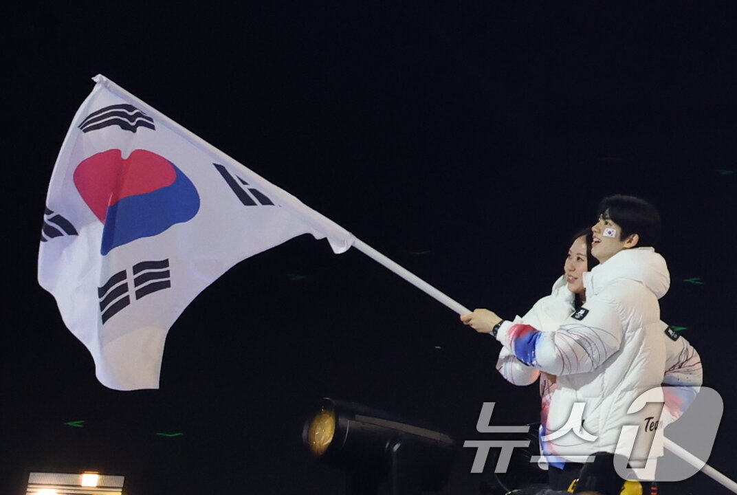 본문 이미지 - 대한민국 선수단 기수 차준환(피겨 스케이팅)과 박지우(스피드 스케이팅)가 6일 오후(현지시간) 이탈리아 밀라노 산시로 올림픽 스타디움에서 열린 2026 밀라노·코르티나담페초 동계올림픽대회 개회식에서 선수단을 이끌고 입장하고 있다. 2026.2.7 ⓒ 뉴스1 김진환 기자
