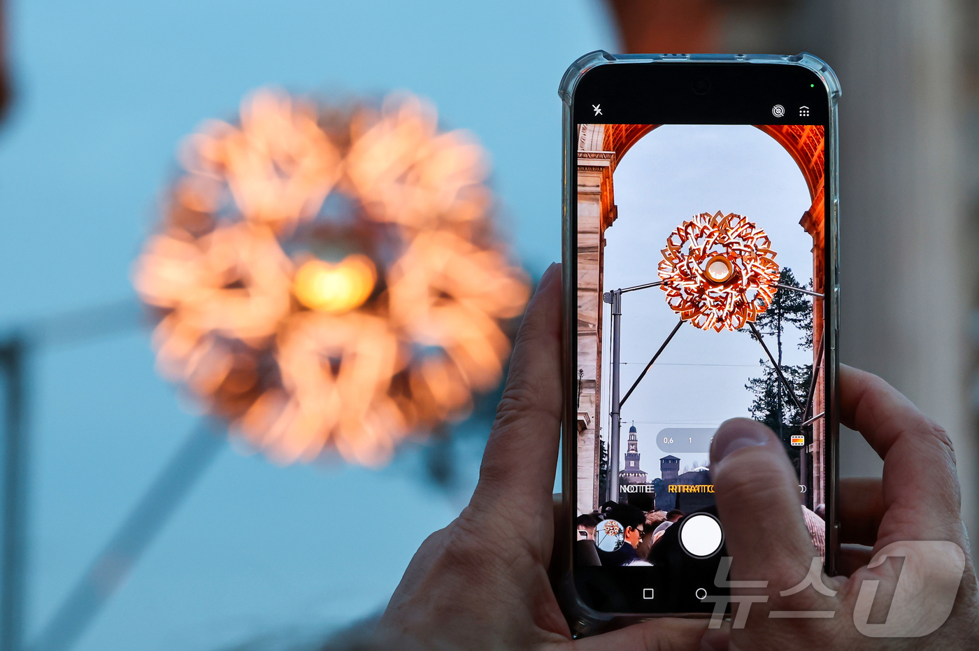 (밀라노=뉴스1) 김진환 기자 = 7일(현지시간) 오후 이탈리아 밀라노 '평화의 아치'(아르코 델라 파체·Arco della Pace) 성화대를 찾은 관광객이 점화된 성화를 스마트 …