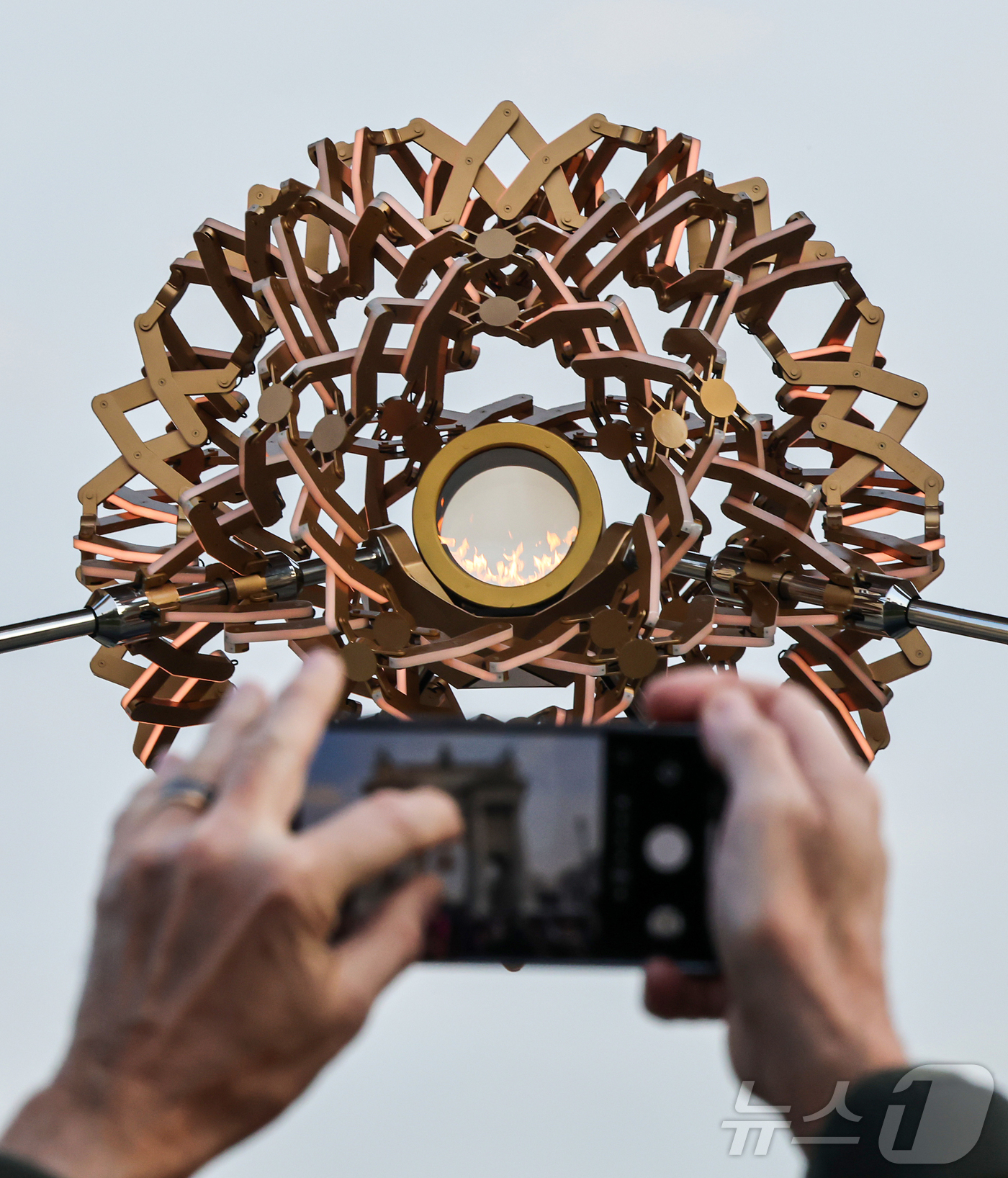 (밀라노=뉴스1) 김진환 기자 = 7일(현지시간) 오후 이탈리아 밀라노 '평화의 아치'(아르코 델라 파체·Arco della Pace) 성화대를 찾은 관광객이 점화된 성화를 스마트 …