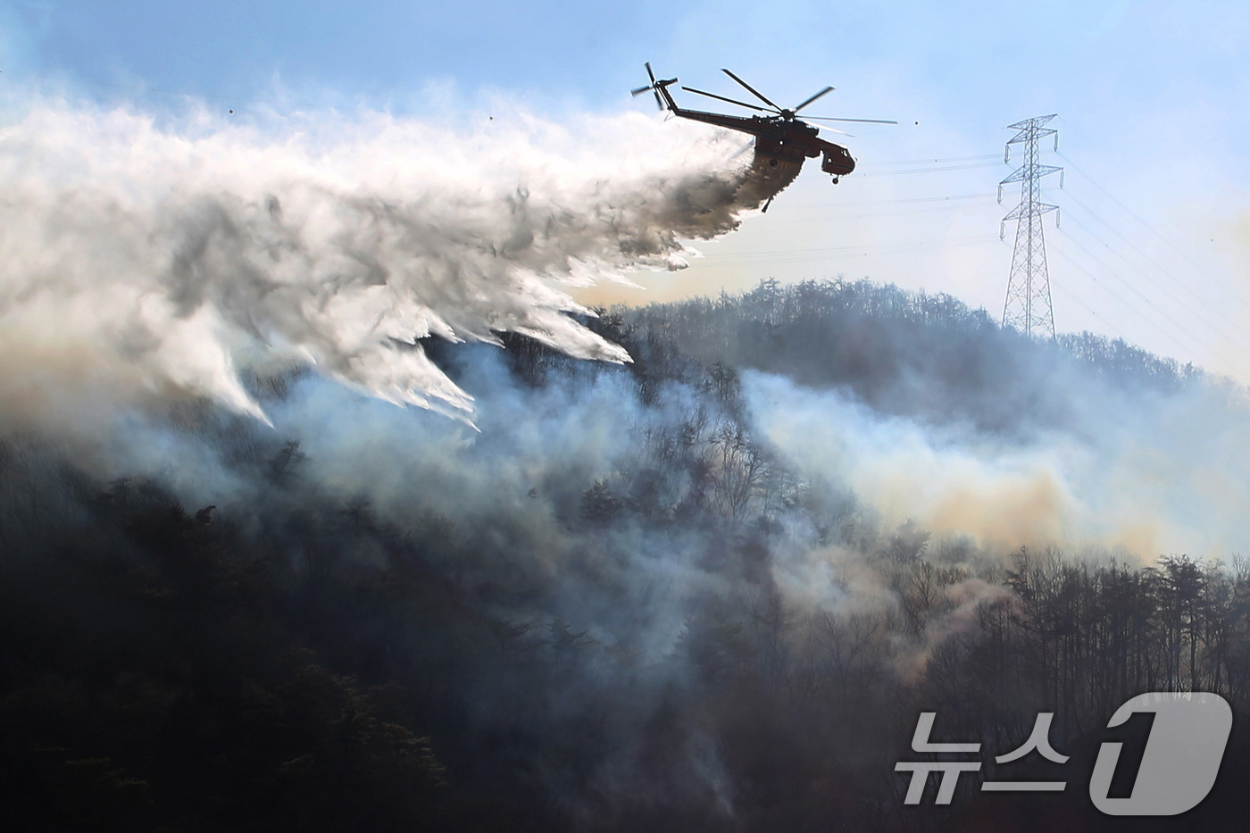 (경주=뉴스1) 공정식 기자 = 8일 오전 경북 경주시 문무대왕면 산불이 강풍을 타고 주변으로 확산하는 가운데 산불 진화에 투입된 헬기가 송전탑 주변을 날아가며 산불을 진화하고 있 …