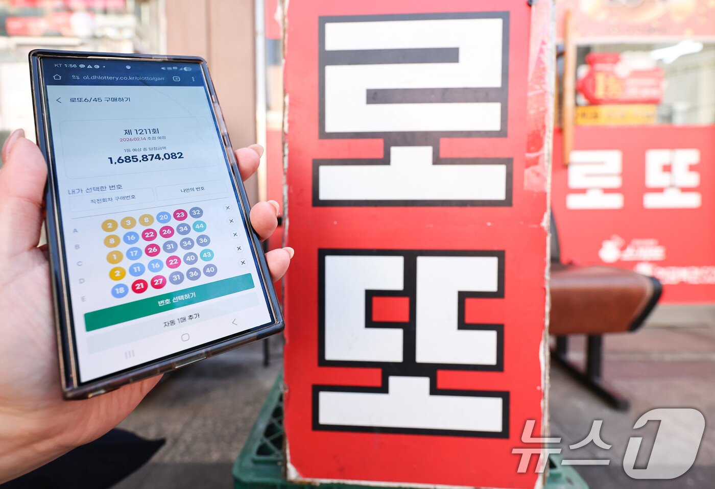 본문 이미지 - 모바일 로또 판매가 시작된 9일 서울 시내의 한 복권 판매점 앞에서 시민이 휴대폰으로 로또를 구매하고 있다. 2026.2.9 ⓒ 뉴스1 최지환 기자