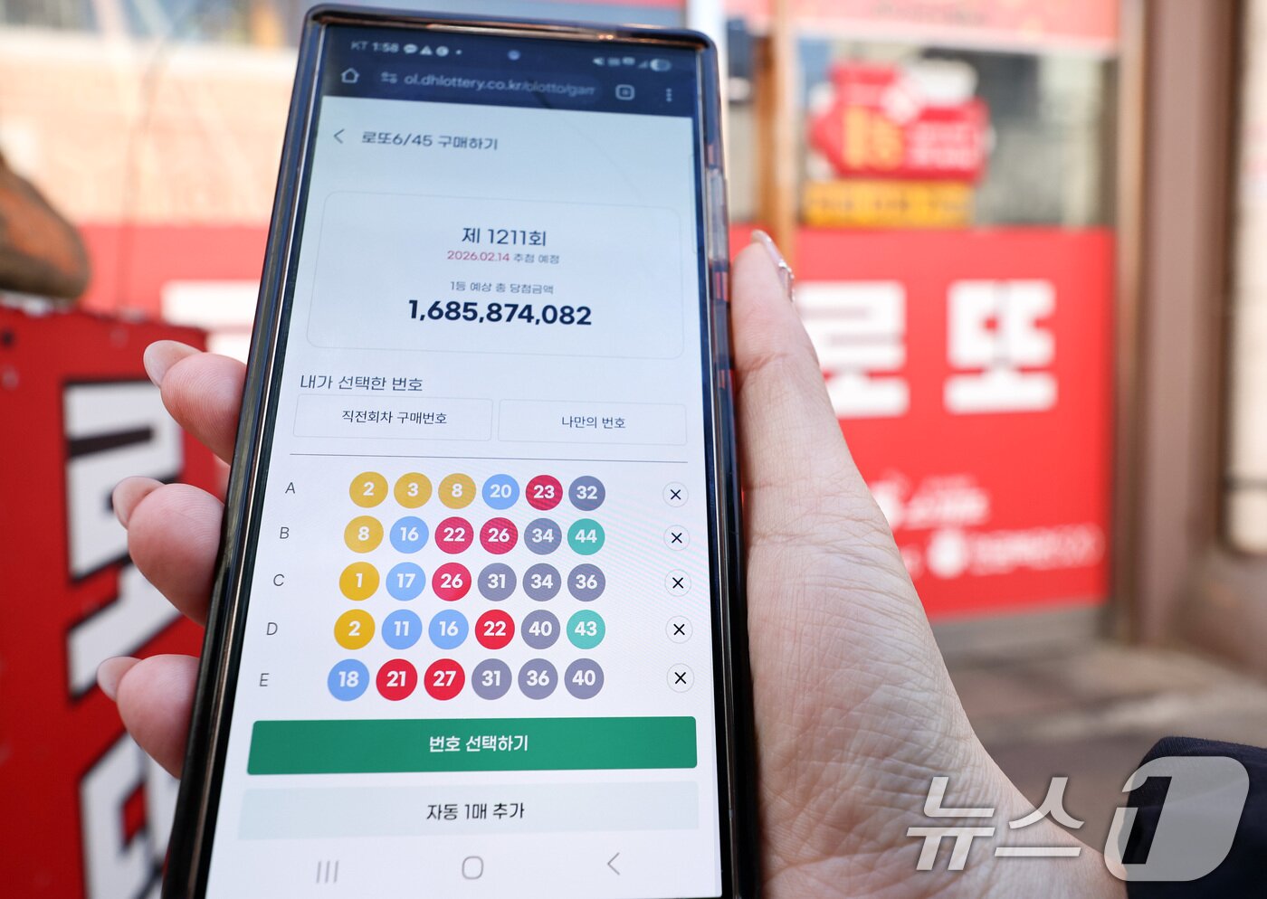 본문 이미지 - 모바일 로또 판매가 시작된 9일 서울 시내의 한 복권 판매점 앞에서 시민이 휴대폰으로 로또를 구매하고 있다. 2026.2.9 ⓒ 뉴스1 최지환 기자