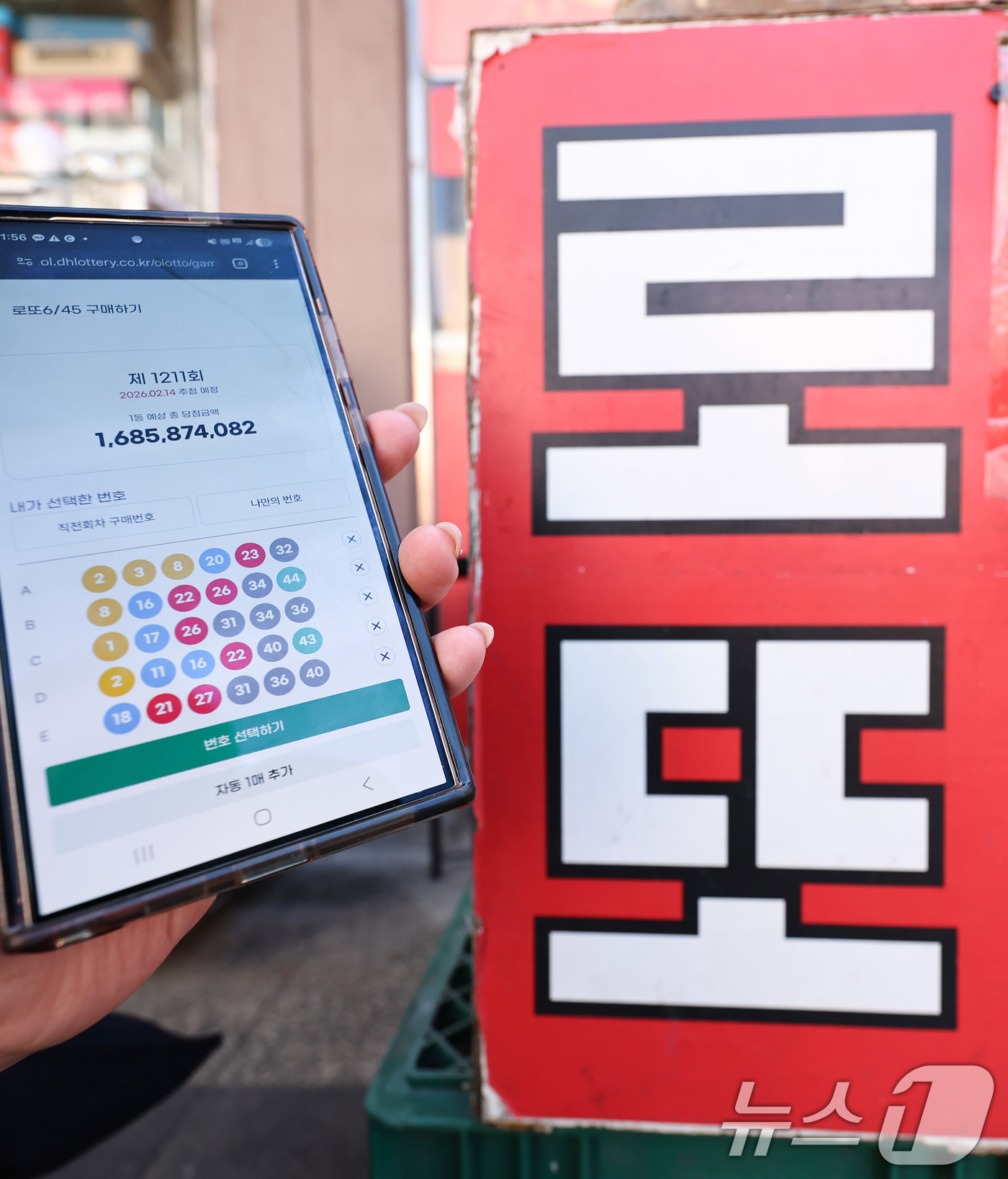 (서울=뉴스1) 최지환 기자 = 모바일 로또 판매가 시작된 9일 서울 시내의 한 복권 판매점 앞에서 시민이 휴대폰으로 로또를 구매하고 있다.이용자는 모바일 동행복권 홈페이지에 가입 …